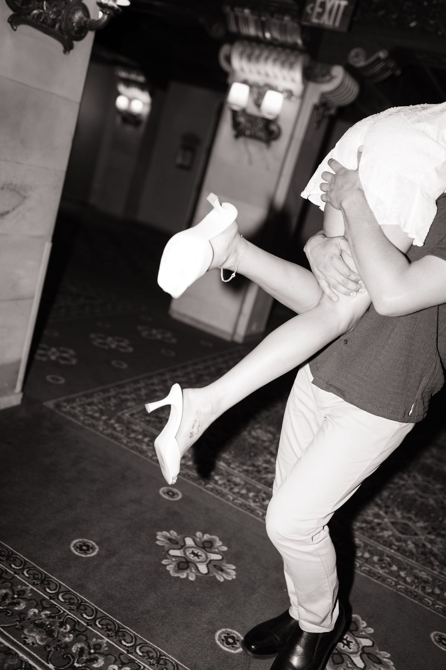 A black and white photo of dancers in an intimate pose on a patterned carpet.