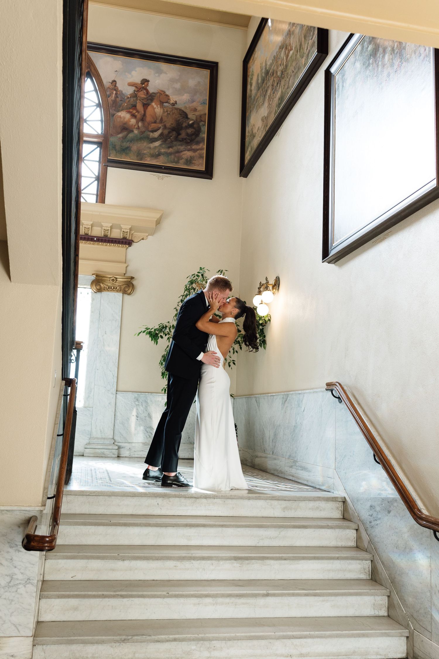 A sequence of wedding photos showing a couple posing on elegant white marble stairs with framed artwork.