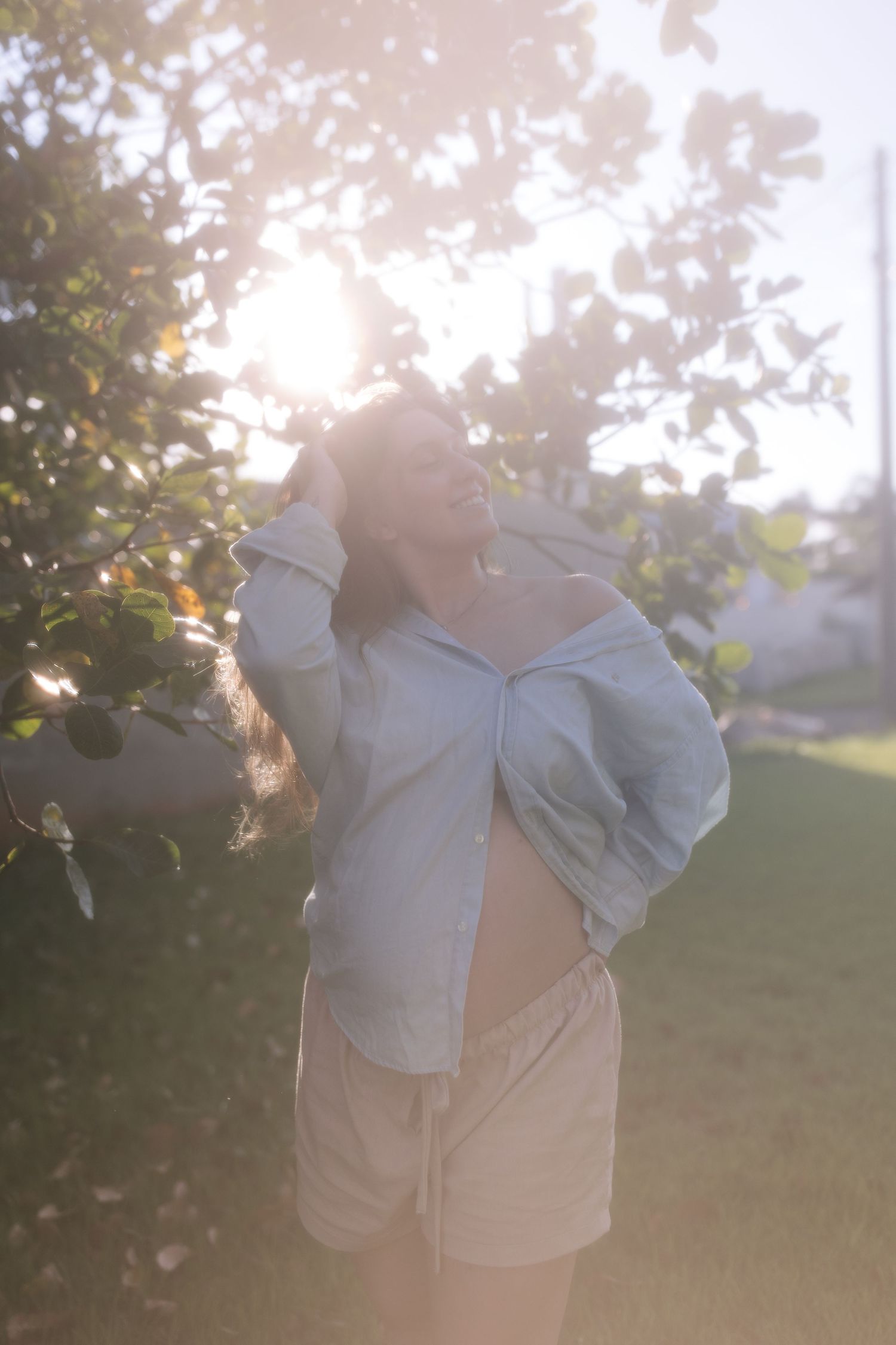 Ethereal outdoor portrait with sunlight filtering through trees in a garden setting.