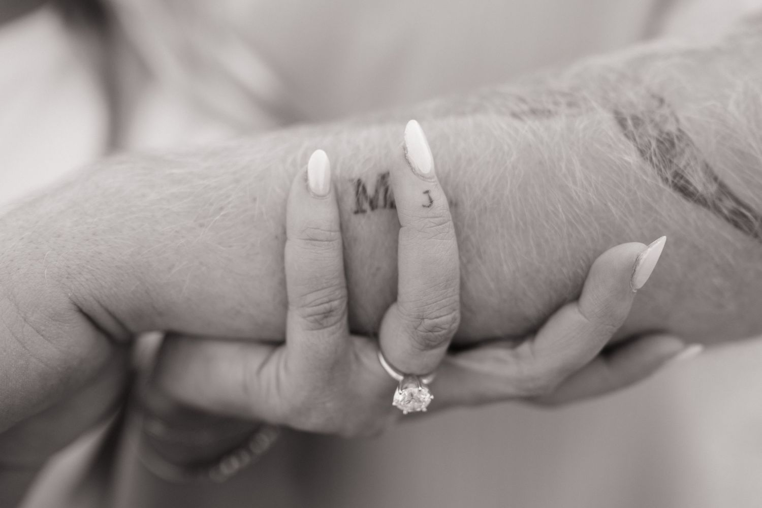 Close-up of hands with engagement rings showing intimate connection.