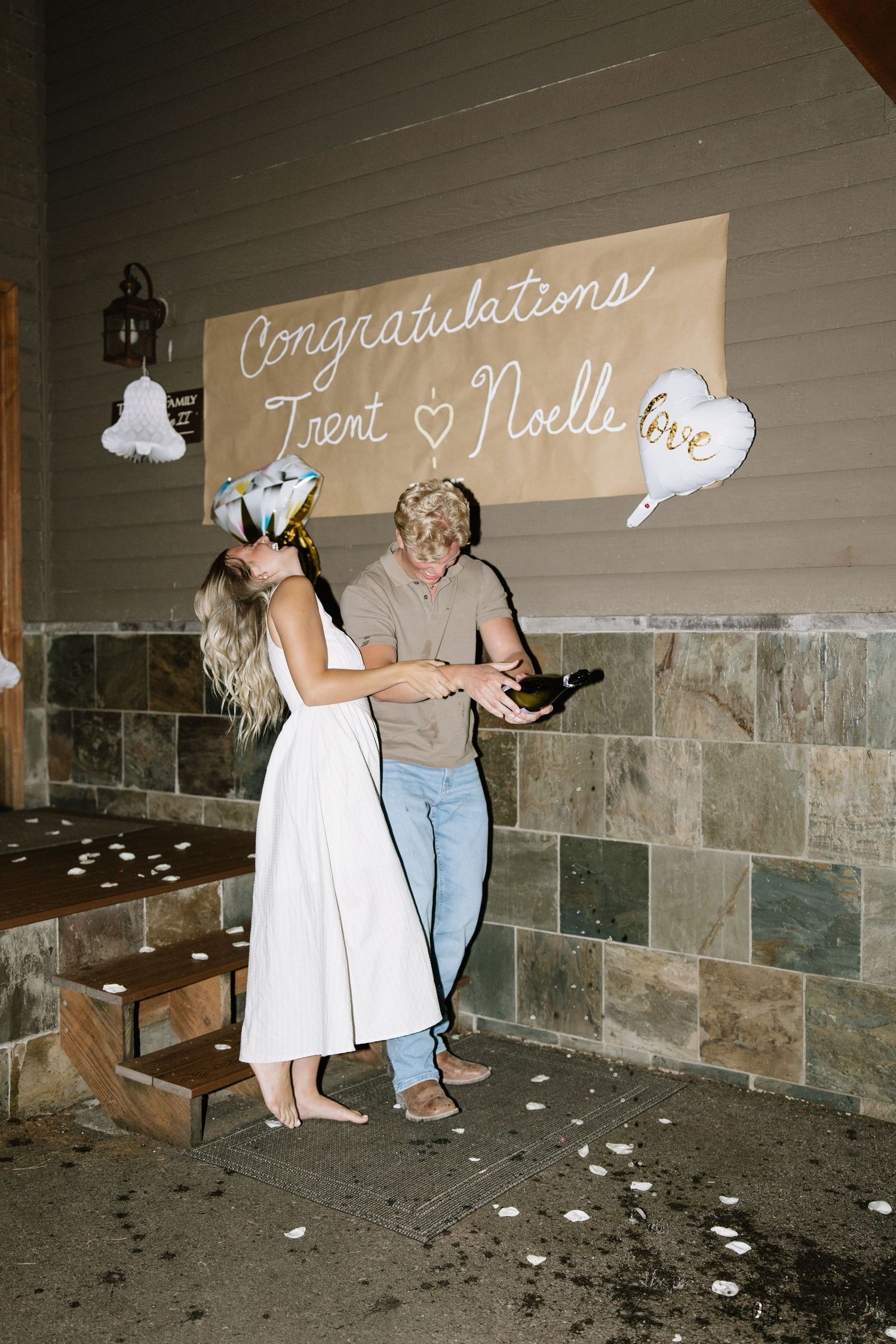 Couple dancing in an indoor space with white text on the wall and confetti scattered on the floor.