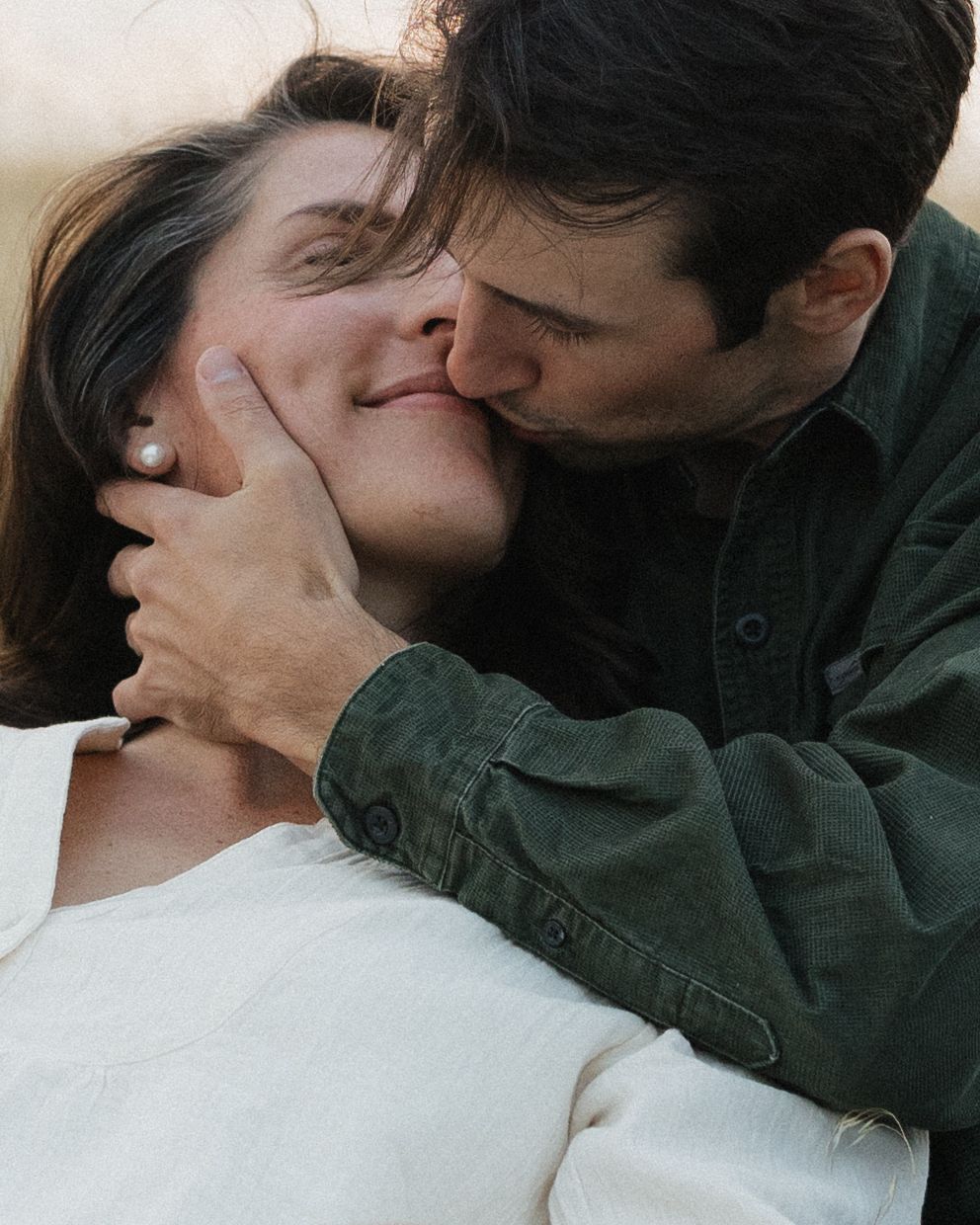 A romantic couple sharing an intimate moment in natural light.