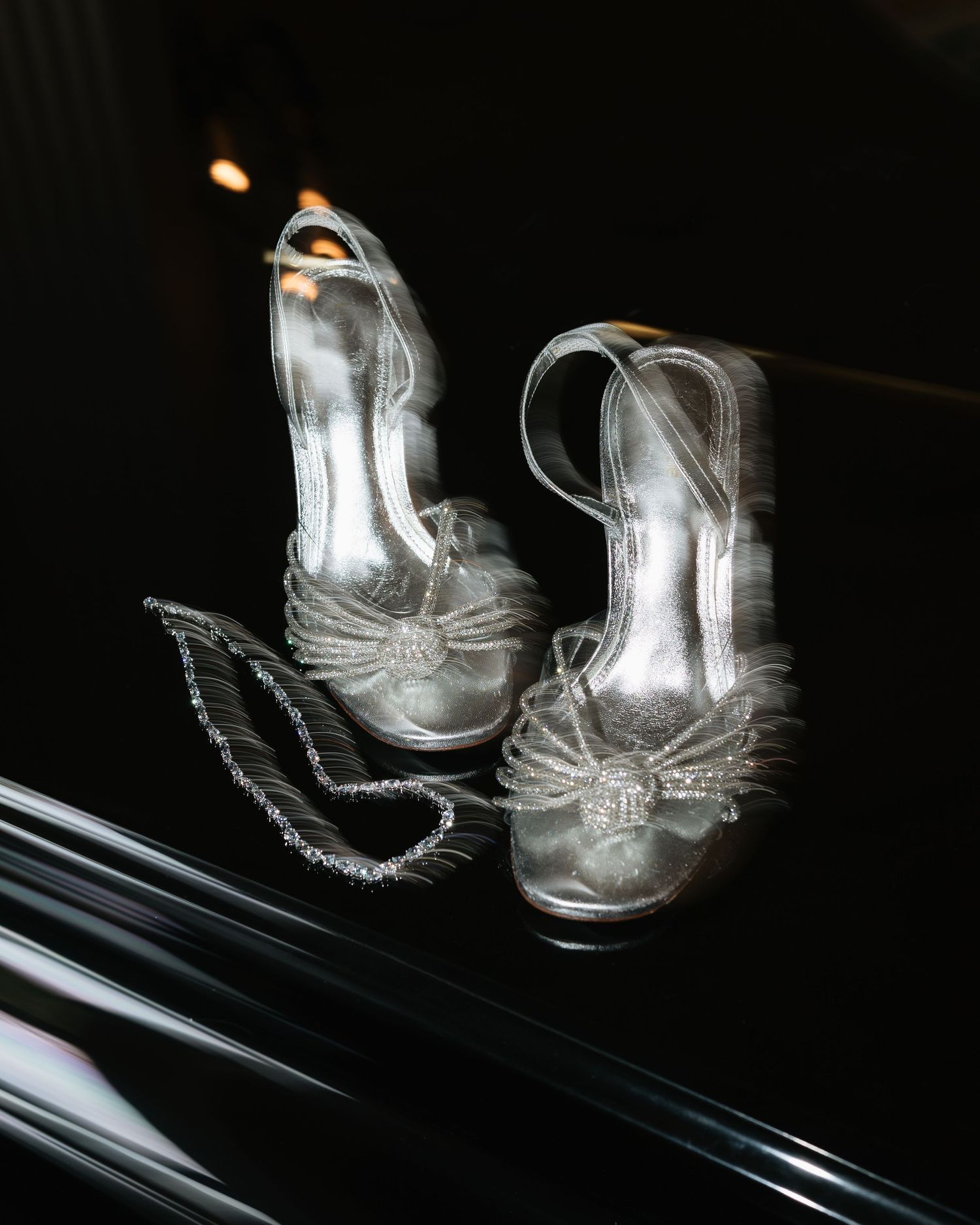 Translucent glass boots with intricate etched designs reflect light against a dark background.