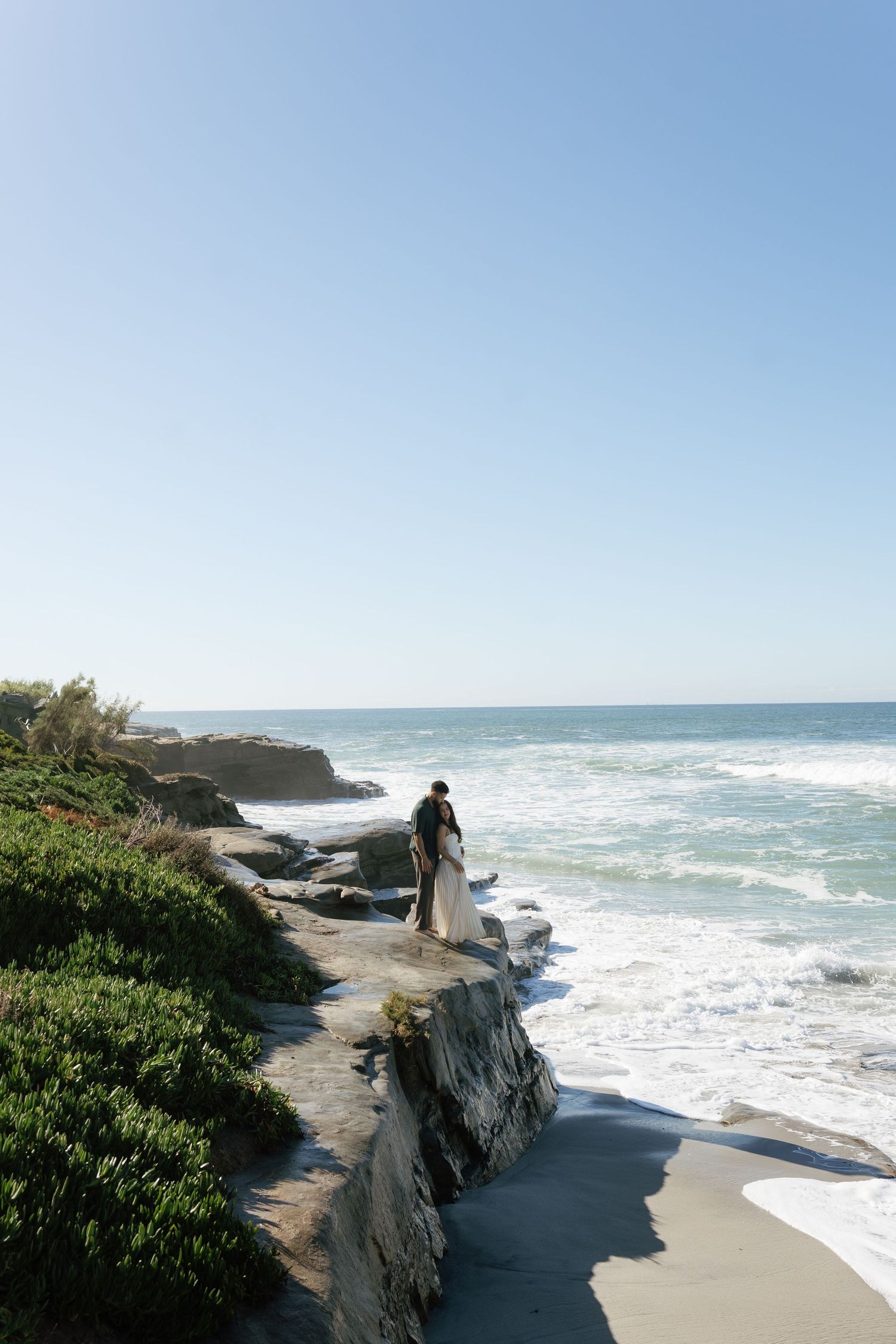 Rugged coastline with waves crashing against rocky cliffs on a bright day.