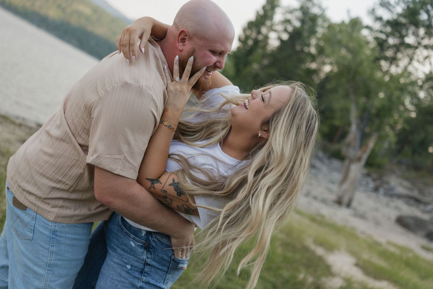 Couple sharing an intimate moment outdoors with natural scenery in the background.
