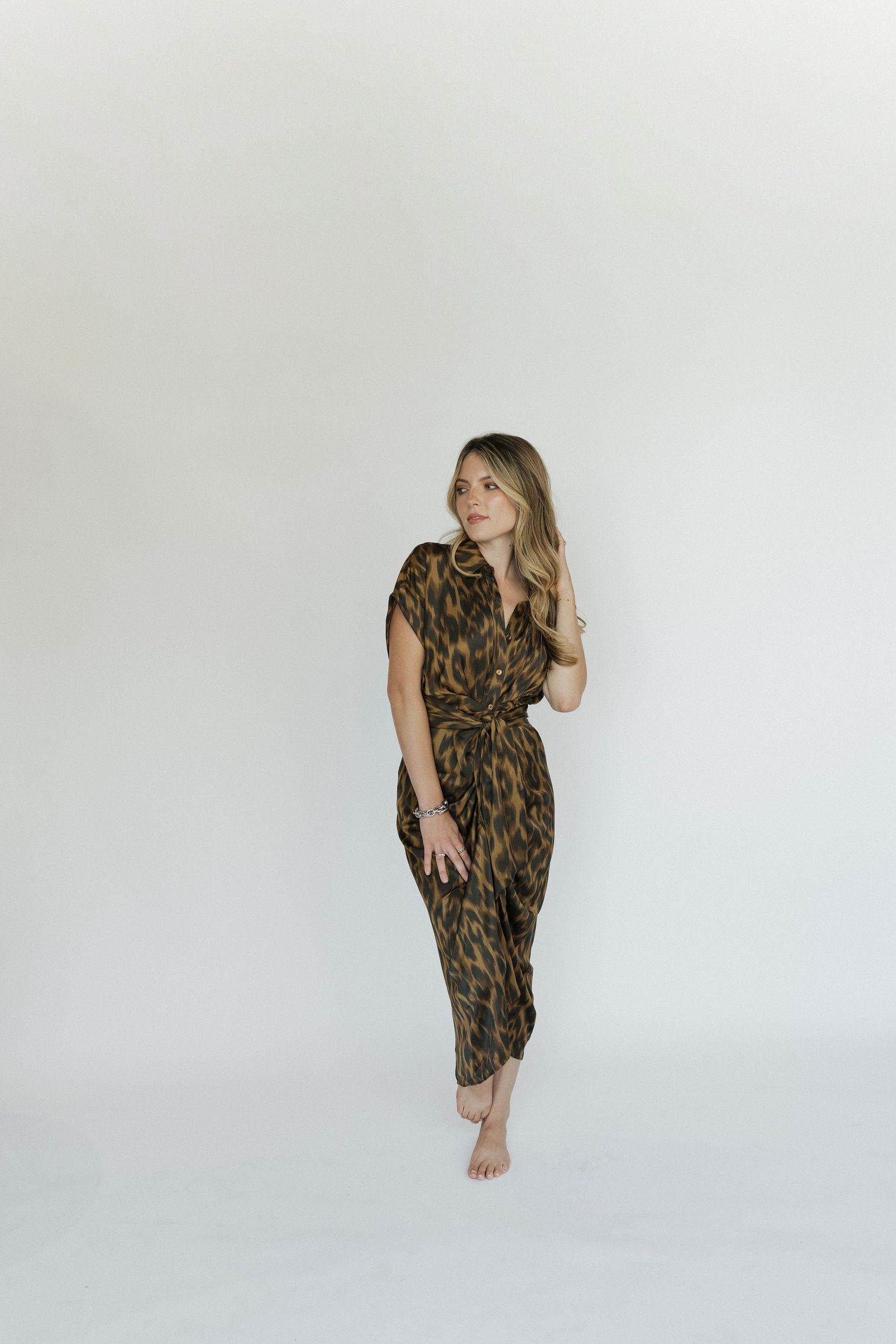 Artistic poses in a leopard print dress during a minimalist studio session.