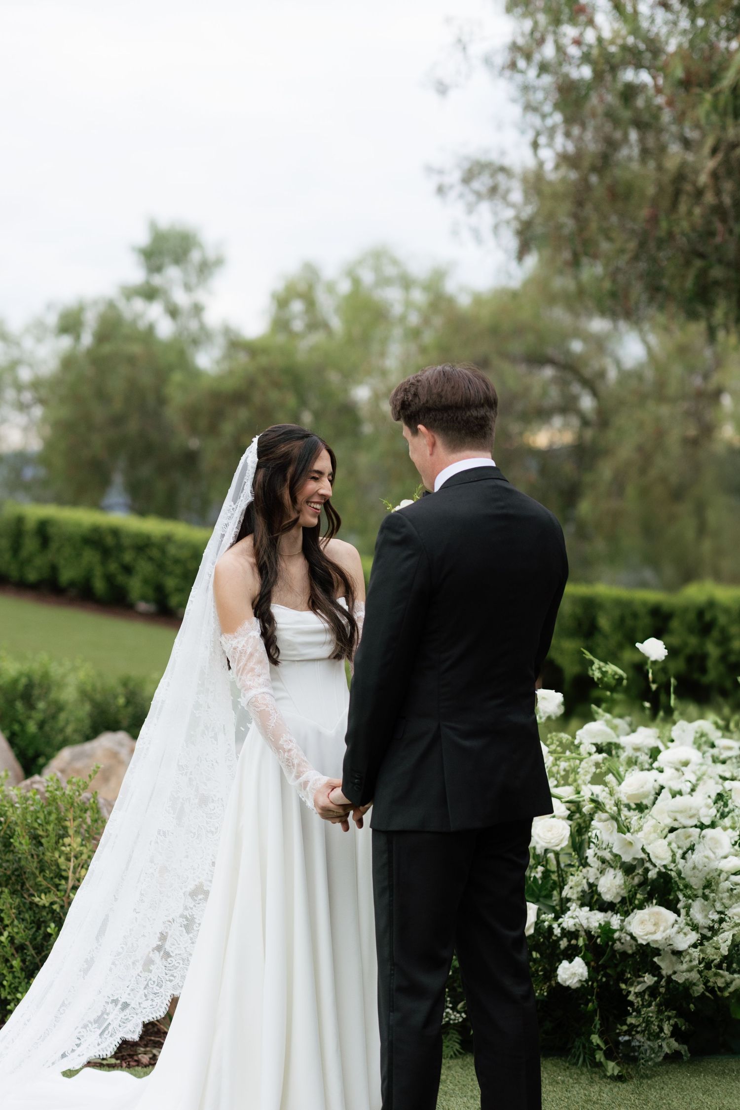 Elegant garden wedding scene with white floral arrangements and flowing veil.
