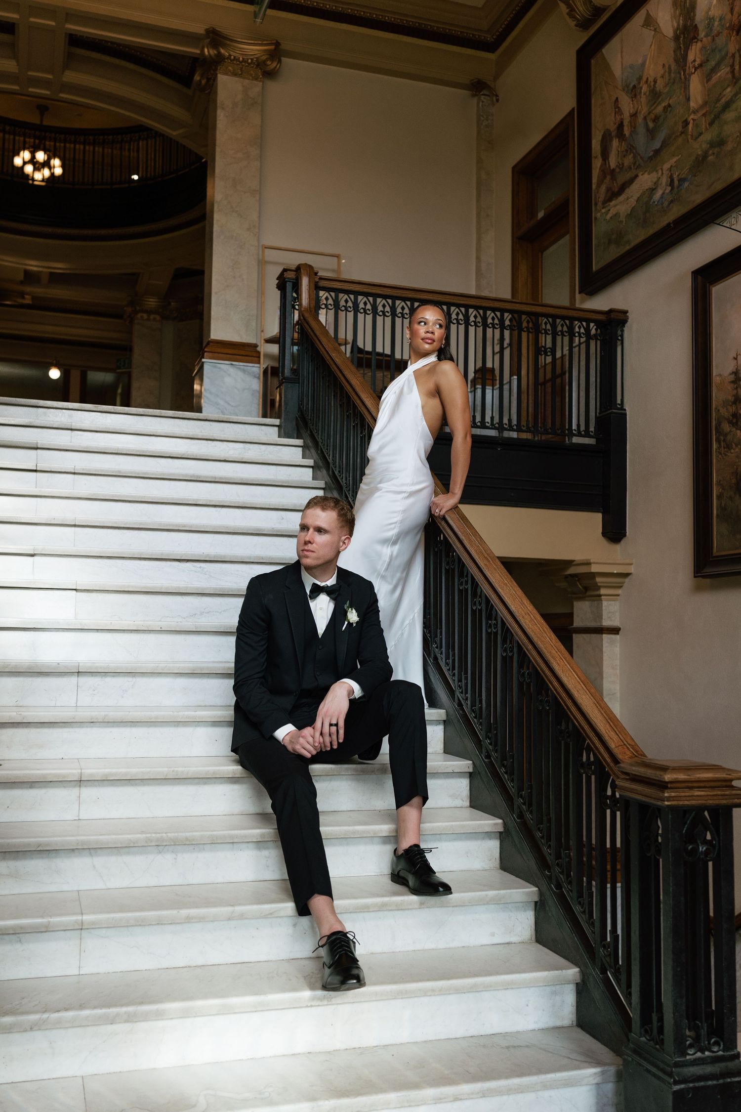Artistic wedding photos featuring a couple in formal attire lounging on white marble stairs.
