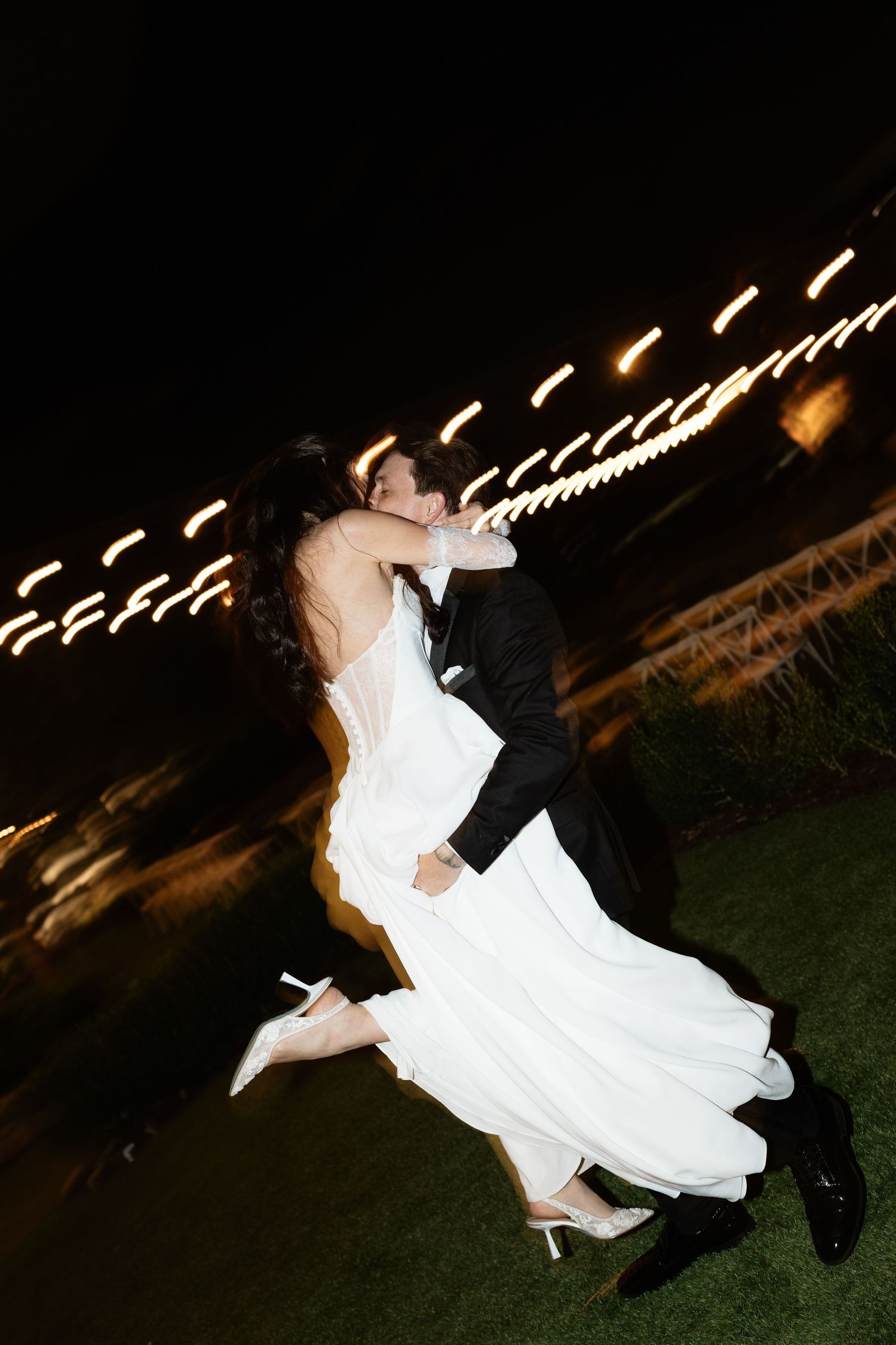 Dynamic nighttime wedding dance captured with motion blur and string lights.
