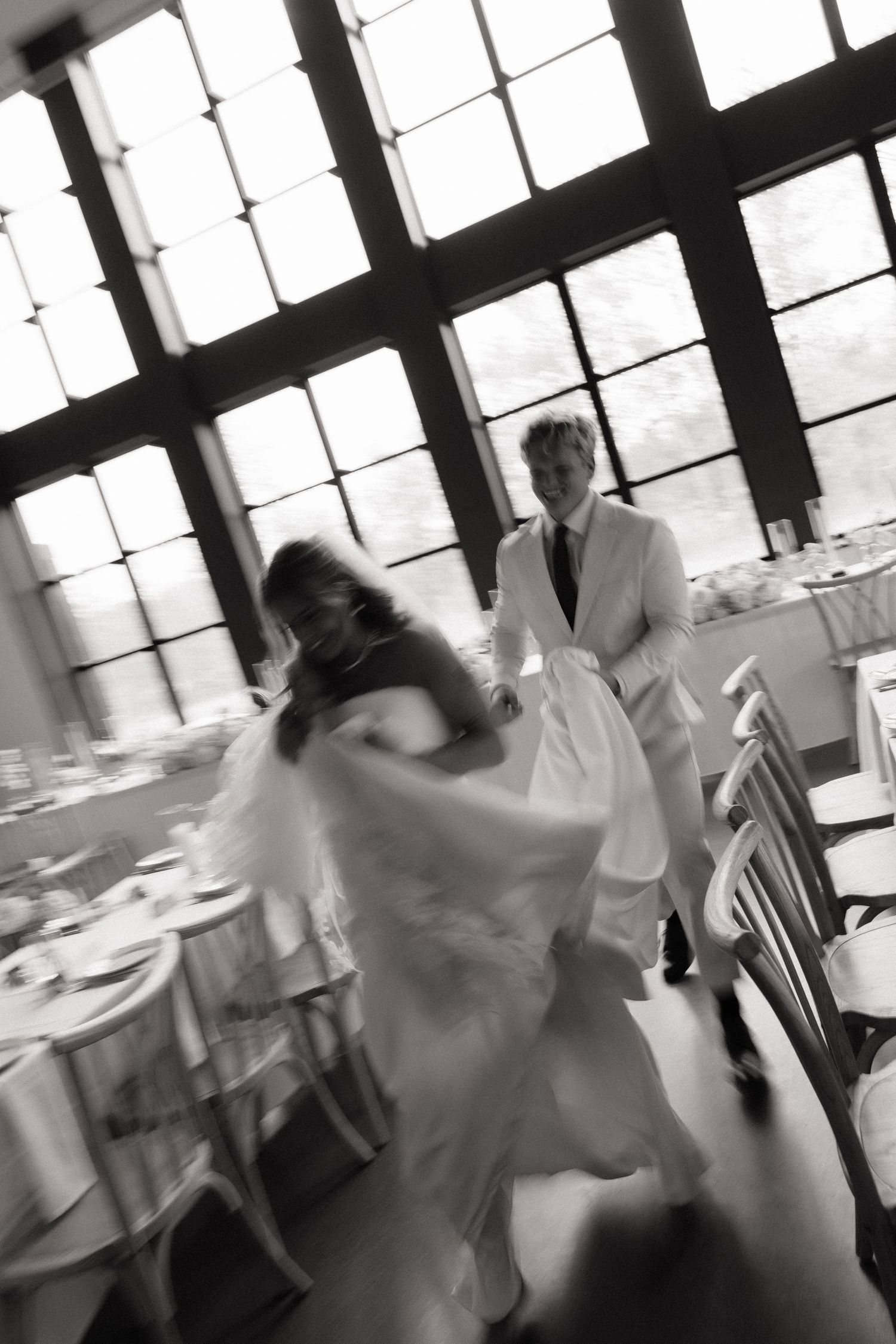 Black and white photo of a bride and groom dancing at their wedding reception in an elegant venue.
