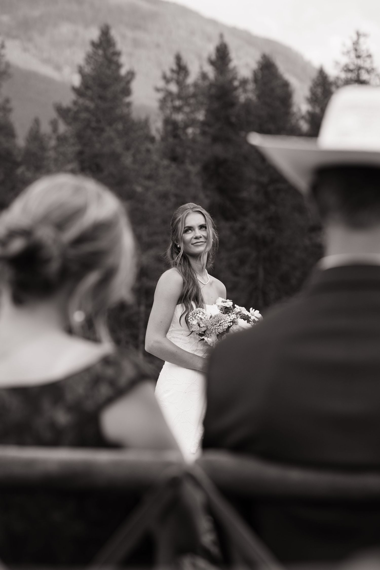 Black and white wedding ceremony photo with mountain landscape in background.