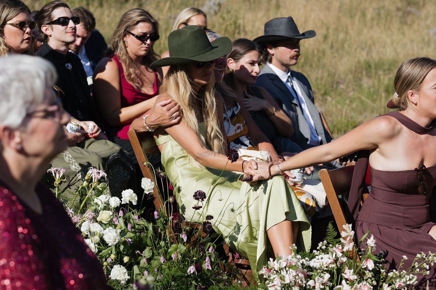 Wedding guests seated outdoors with floral decorations in mountain setting.