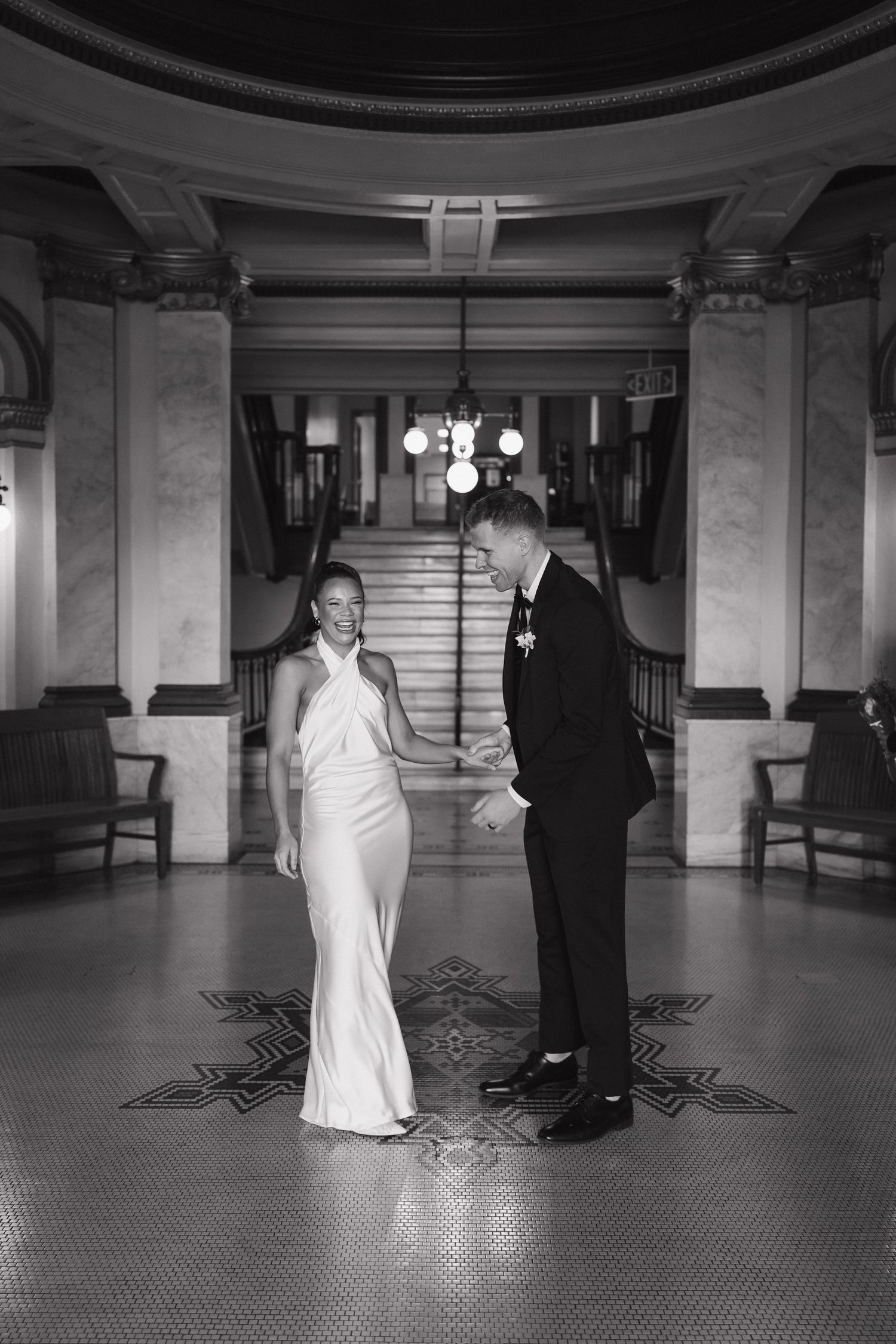 Black and white photos of a bride in white gown and groom in tuxedo on a patterned floor.