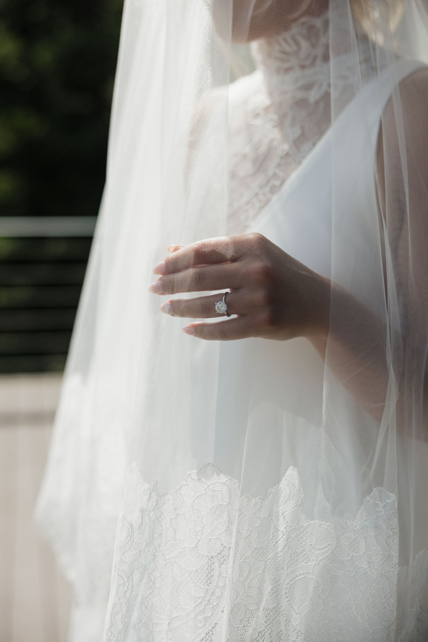 Close-up of bride's hand showing wedding ring through delicate lace veil.