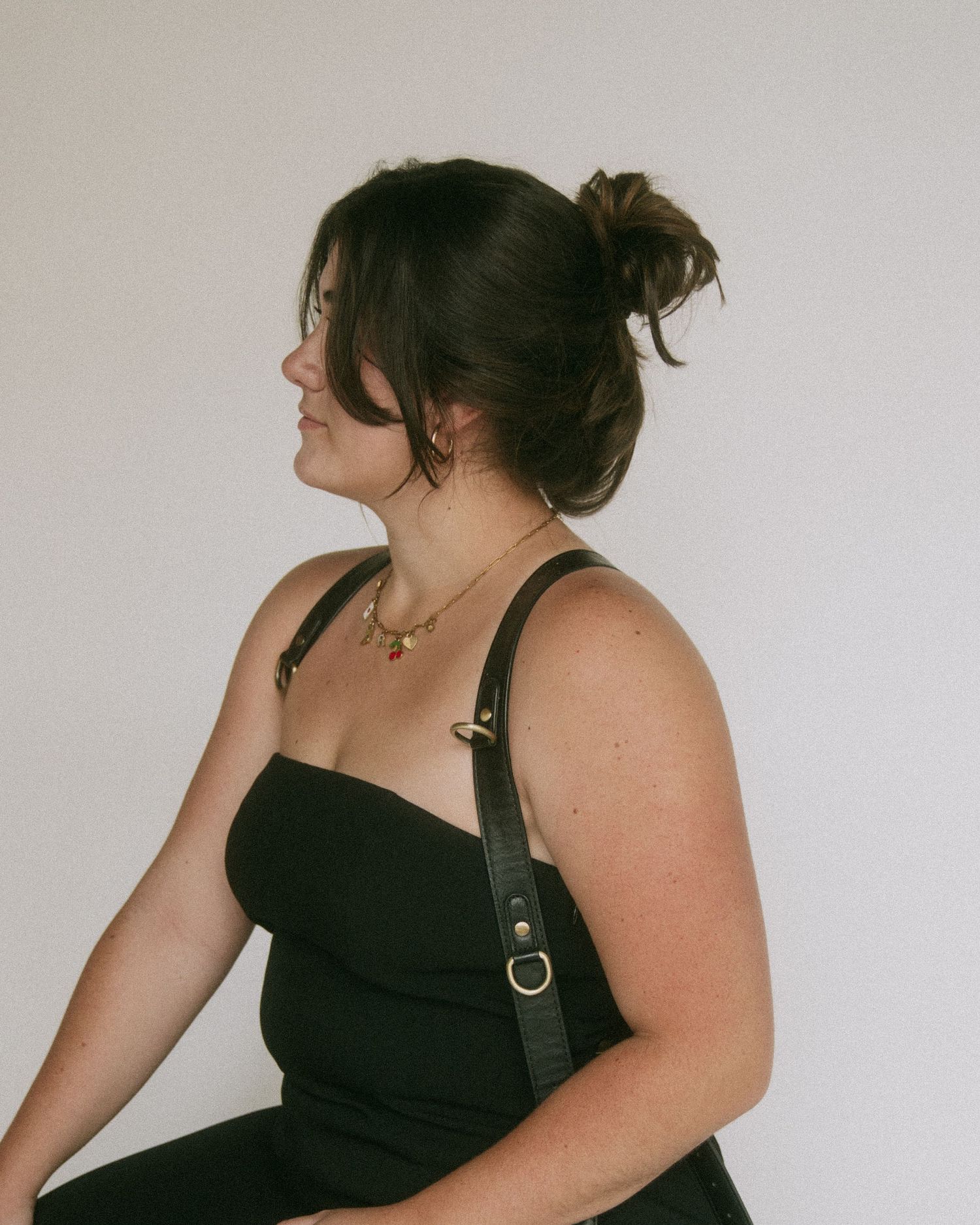 A person in a black dress poses against a white background in a series of four artistic portrait shots.