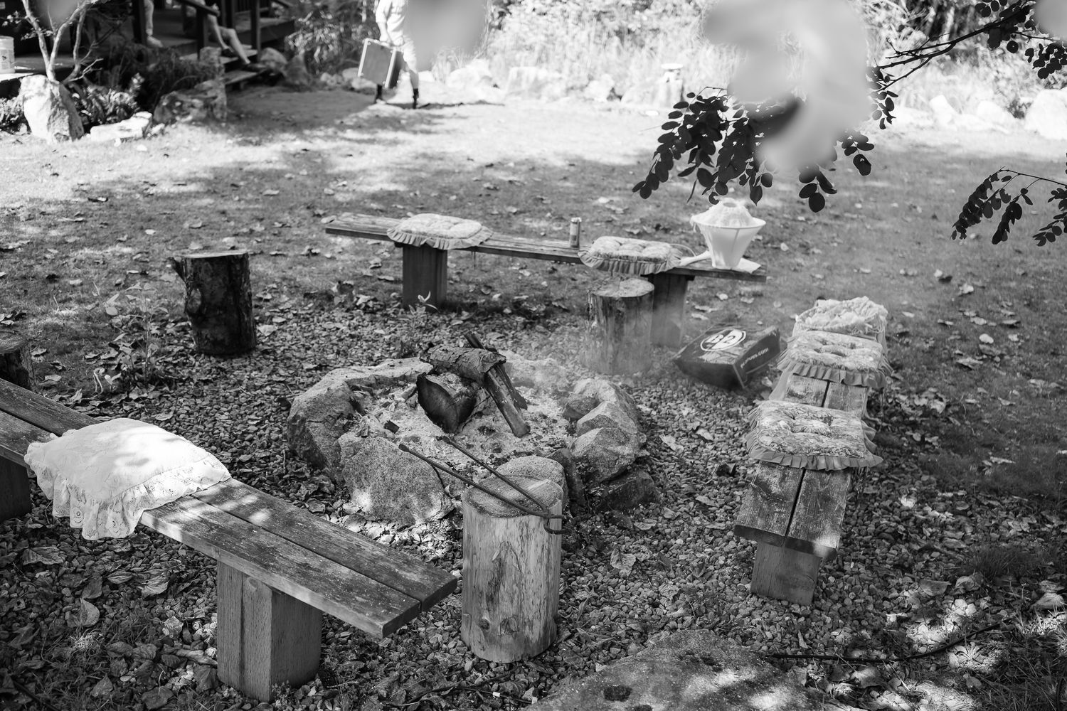 Black and white documentary shot of outdoor wooden bench seating area at mountain ranch