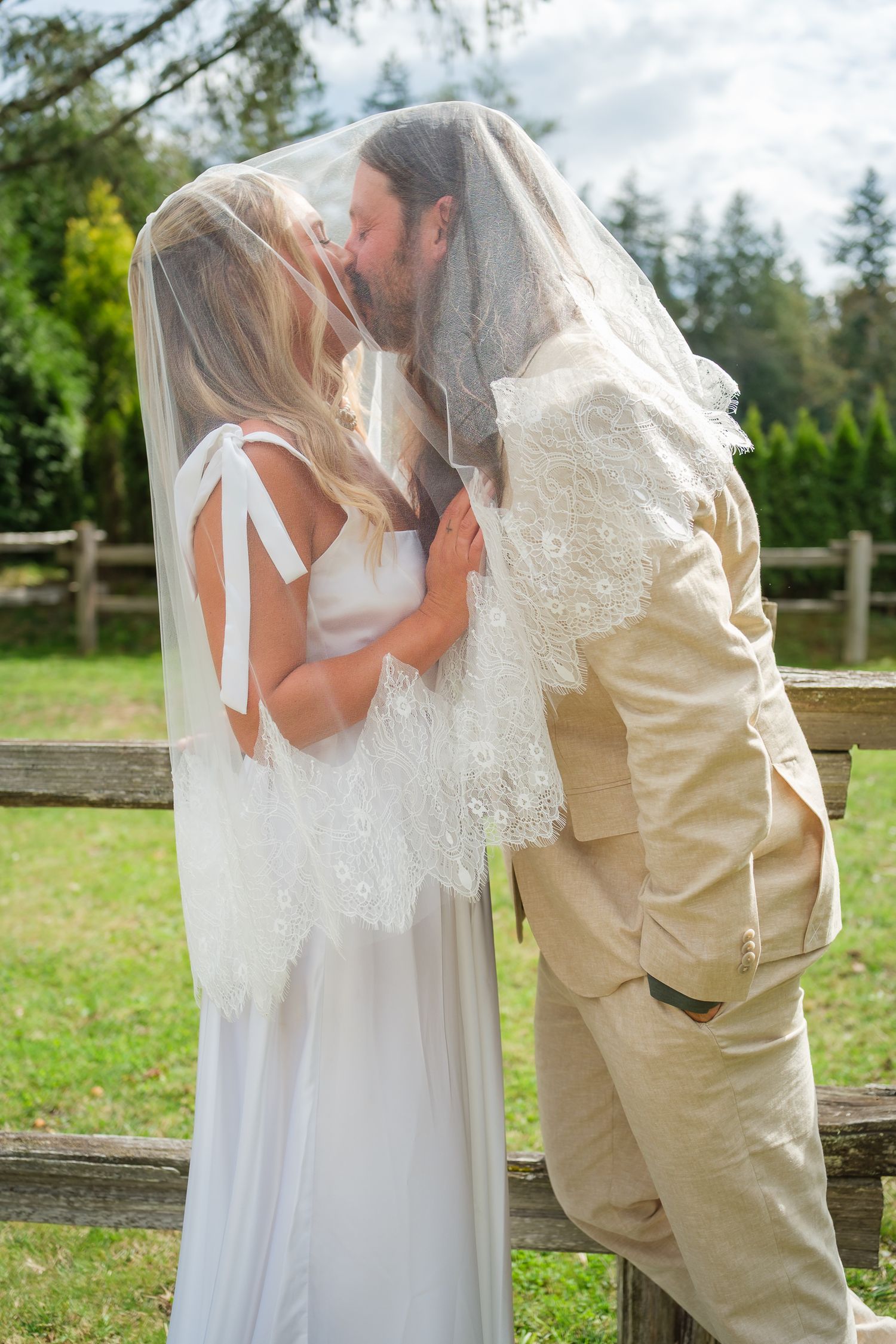 Bride and groom kissing under lace veil during outdoor elopement first look