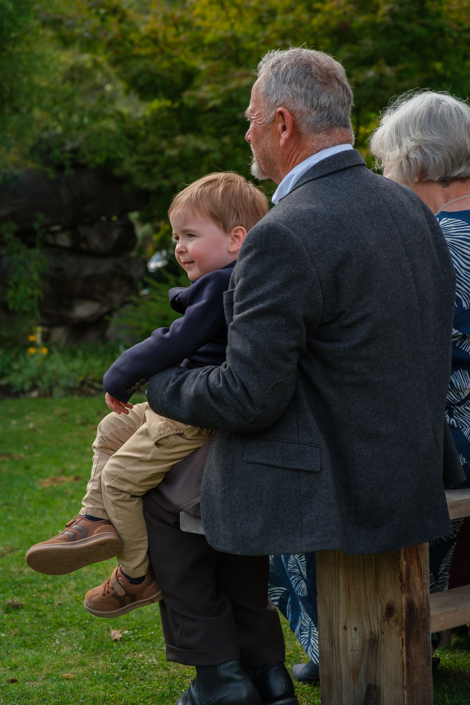 Candid wedding guest photography of family member holding young boy during ceremony