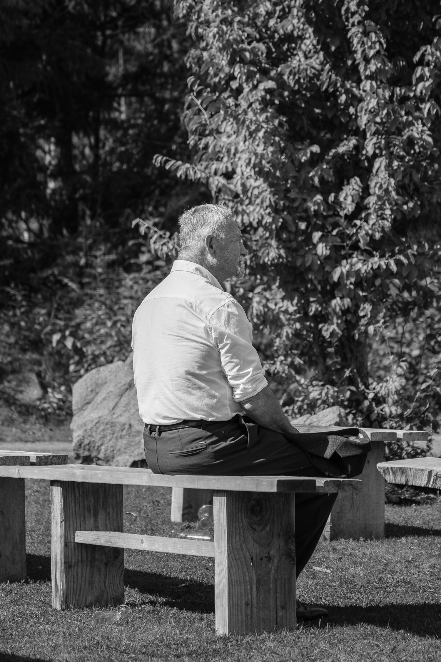 Candid black and white shot of brides father seated outdoors before wedding ceremony