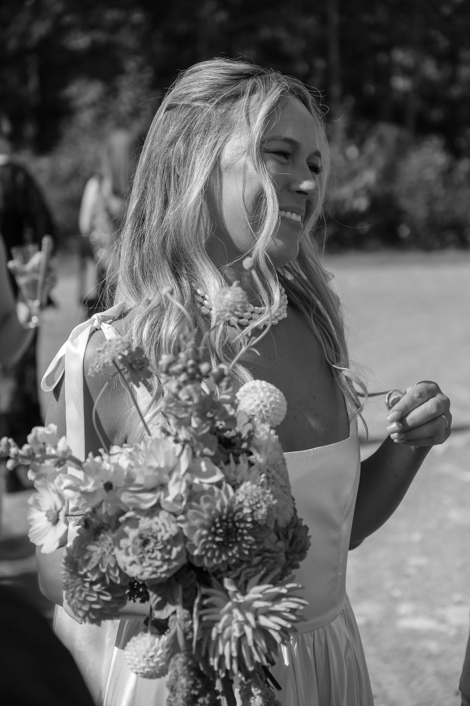 Black and white portrait of smiling bride holding native floral bouquet outdoors