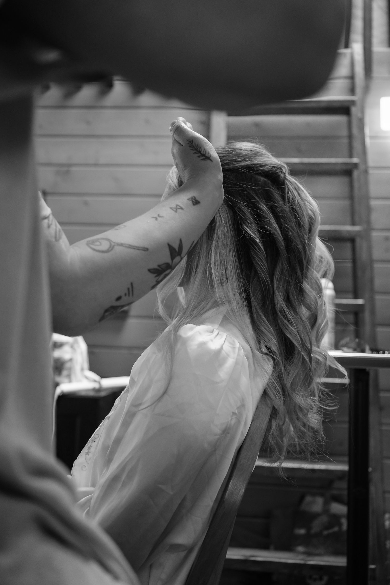 Candid black and white prep photo of bride getting hair styled before elopement
