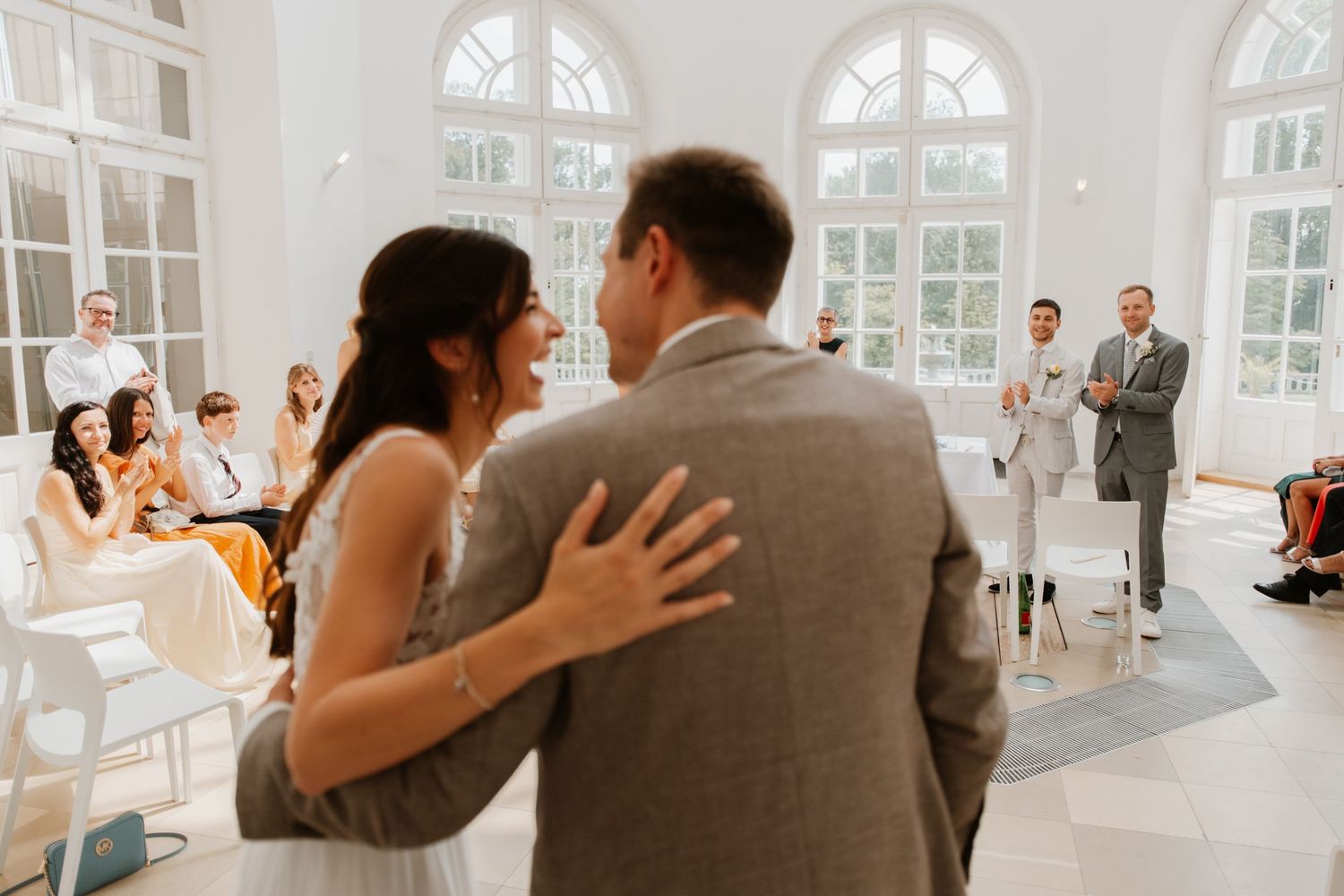 Bride and groom share a joyful first dance moment at their elegant white wedding reception venue.