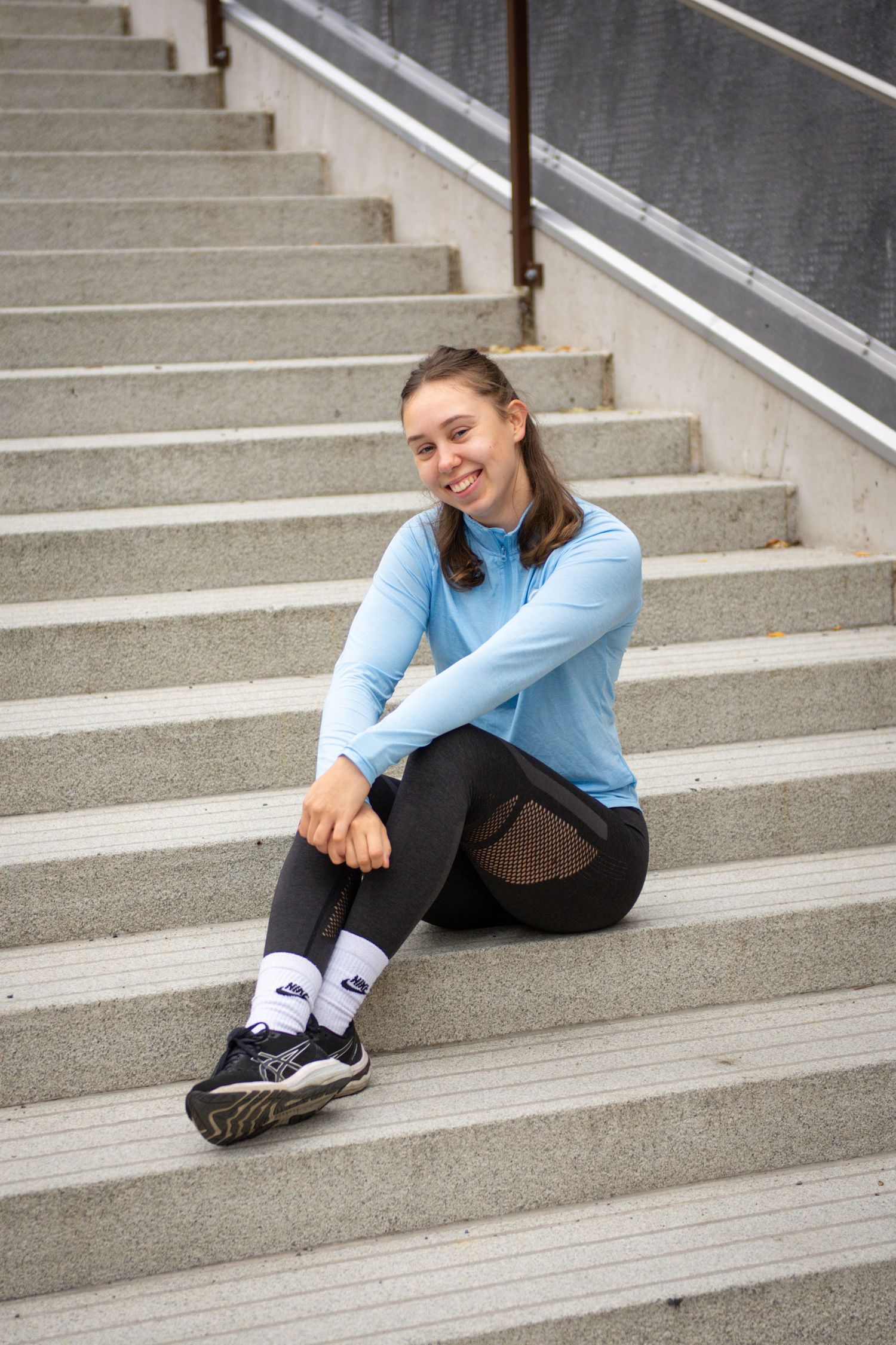 Hyvinvointivalmentaja ja Personal Trainer Frida Heinonen treenivaatteet päällä portailla.