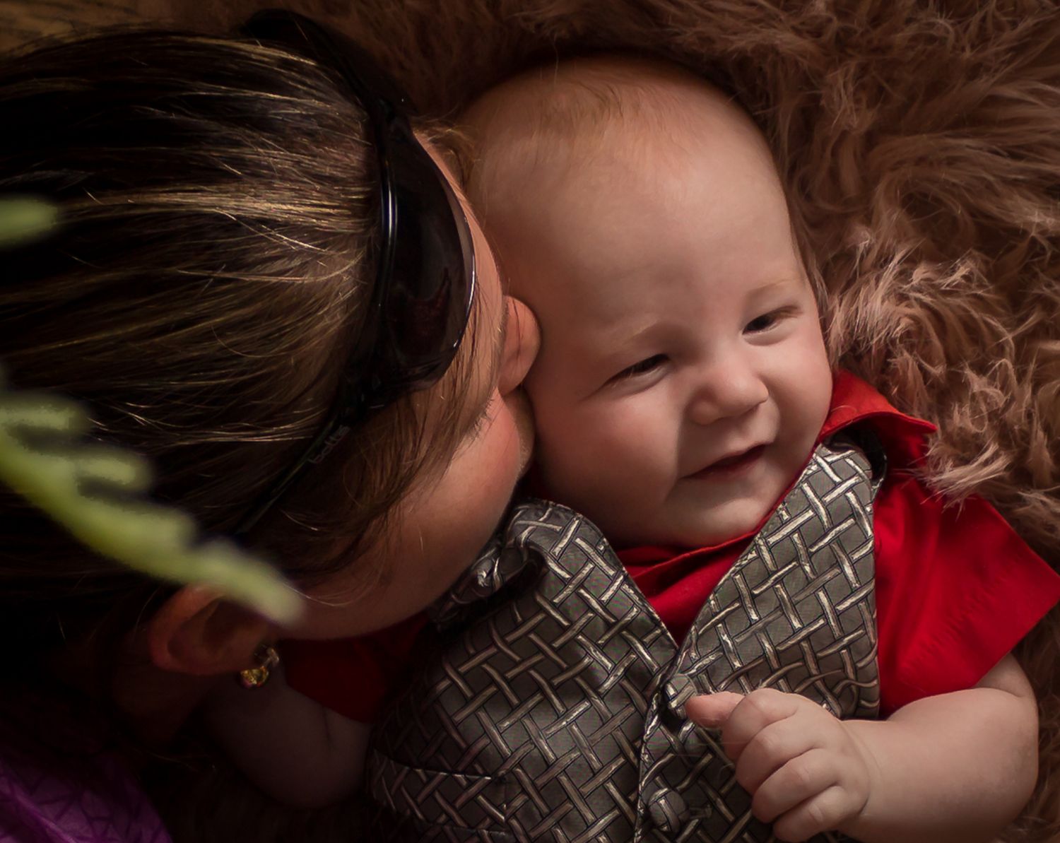 Close-up of a smiling baby being cuddled by an adult.