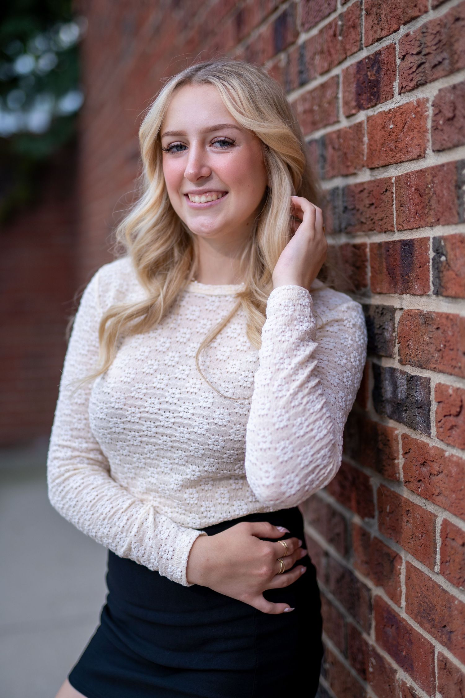 Female Senior Portrait with white sweater against a brick wall