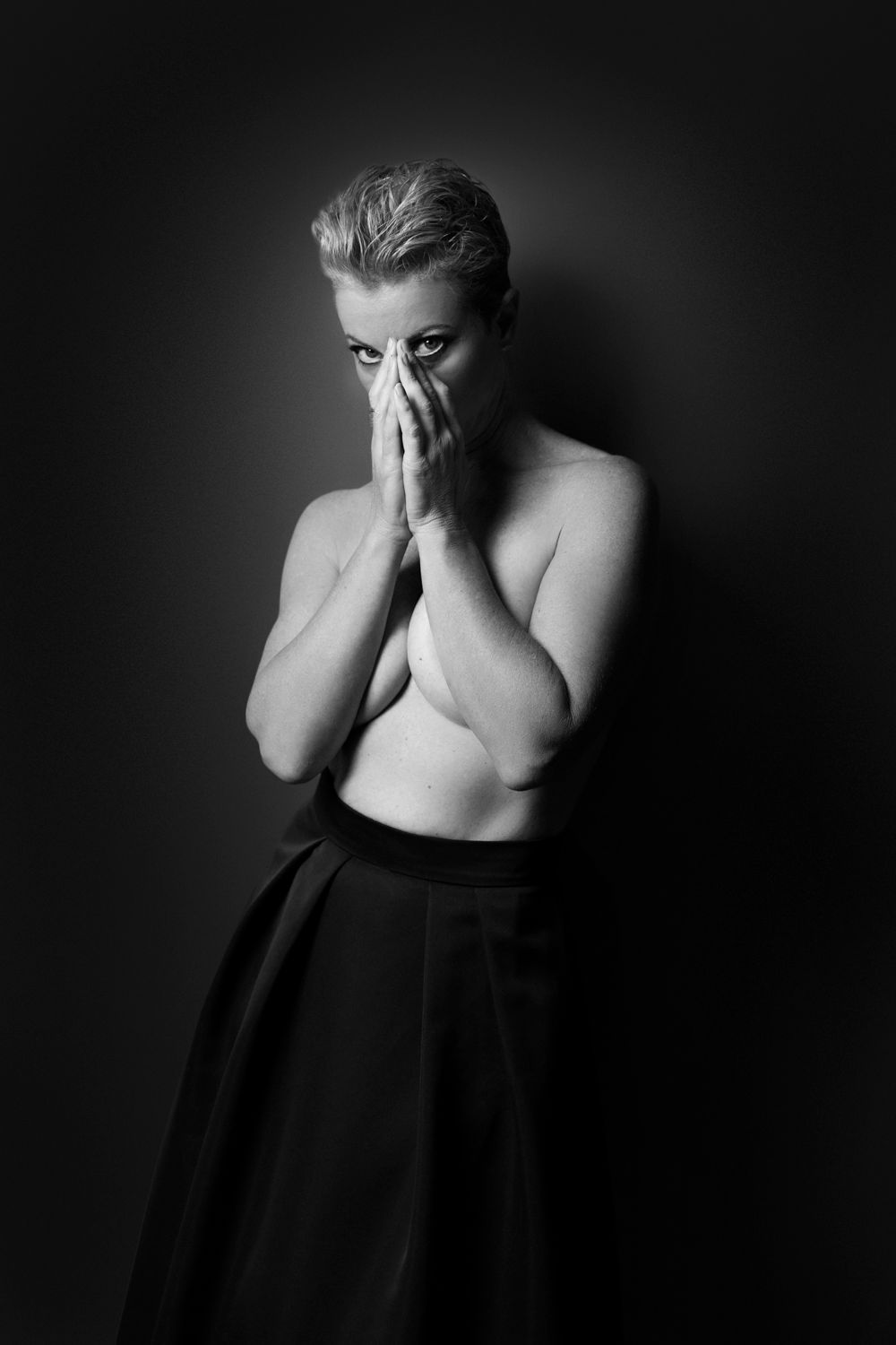 Black and white portrait of short-haired woman covering face with hands.