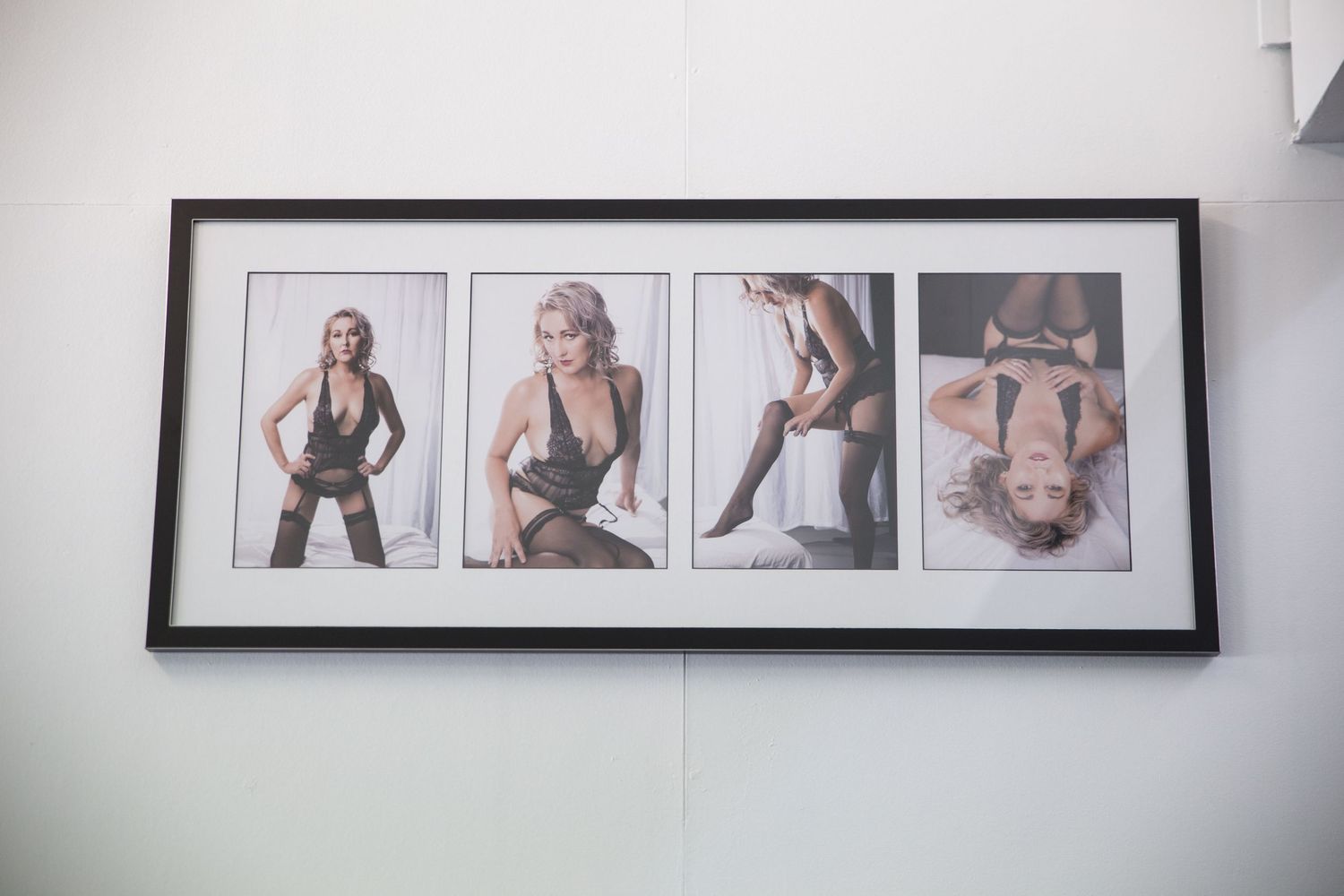 Framed collage of four boudoir photos featuring a blonde woman in black lingerie displayed on a white wall.