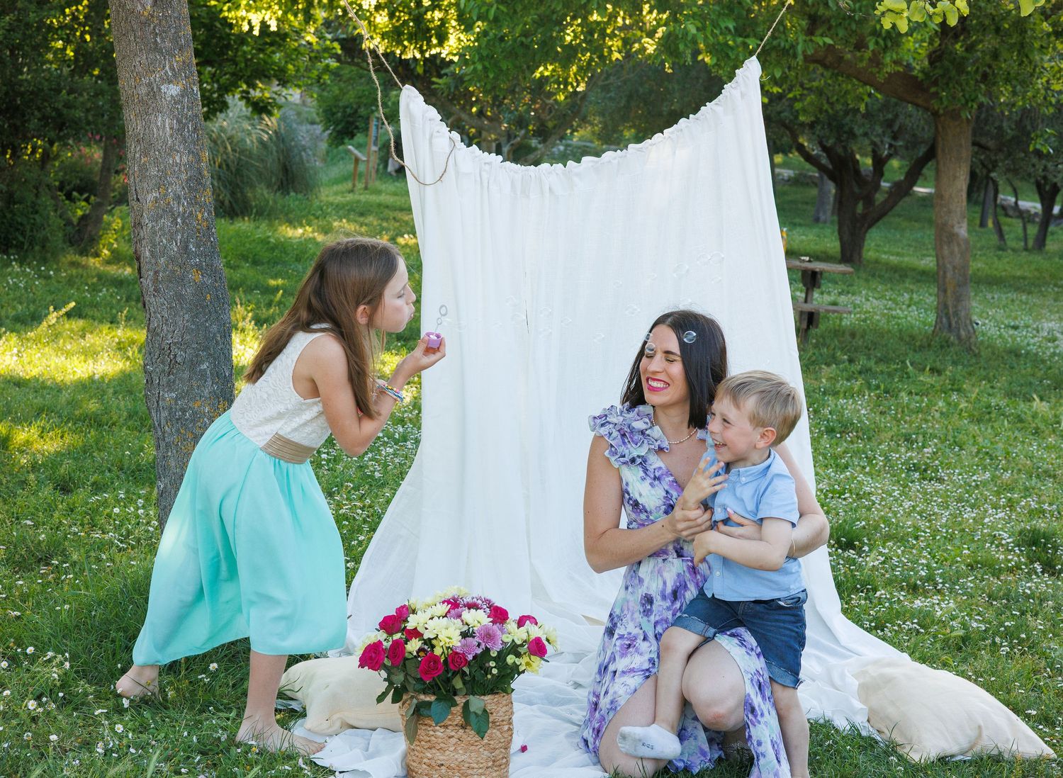 Une maman rit avec ses deux enfants pendant une séance photo famille en extérieur.
