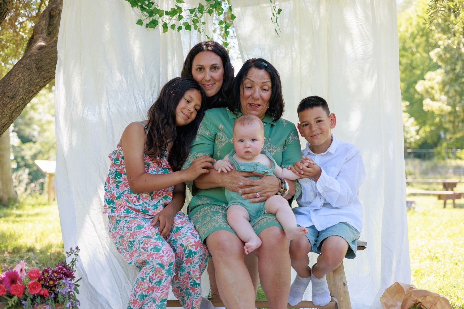 Une famille multigénérationnelle pose ensemble avec un bébé pendant une séance photo famille en extérieur.