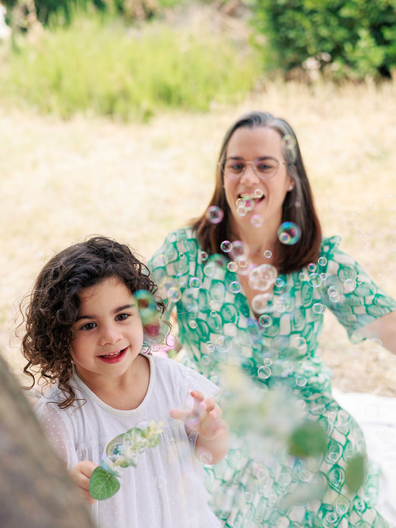 Une maman et ses filles jouent avec des bulles pendant une séance photo au parc dans le Gard