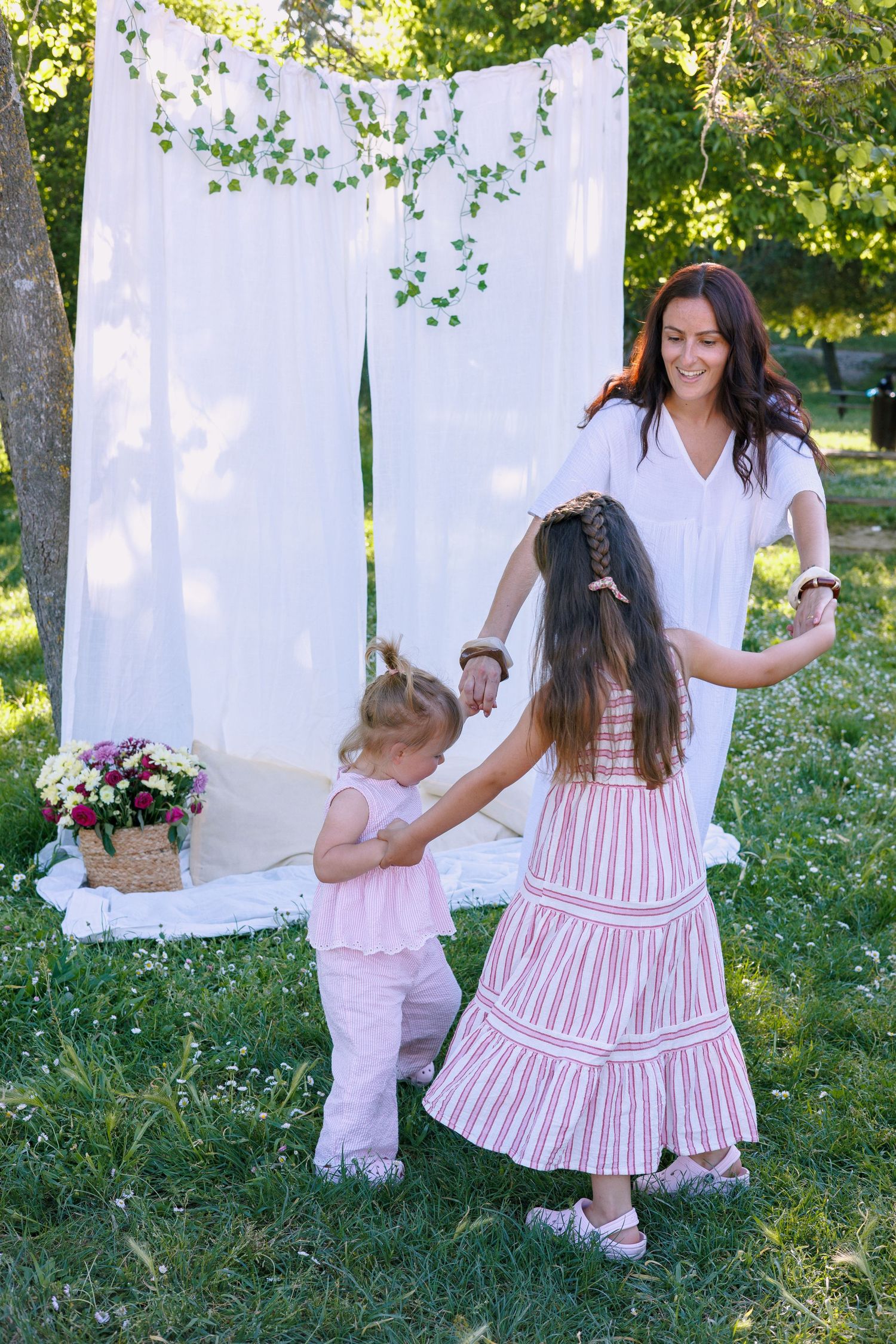 Une maman joue avec ses deux filles pendant une séance photo famille en extérieur.