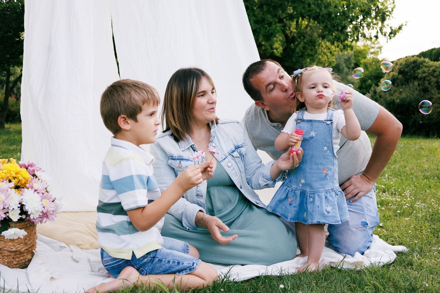 Une famille joue ensemble avec des bulles pendant une séance photo famille en extérieur.