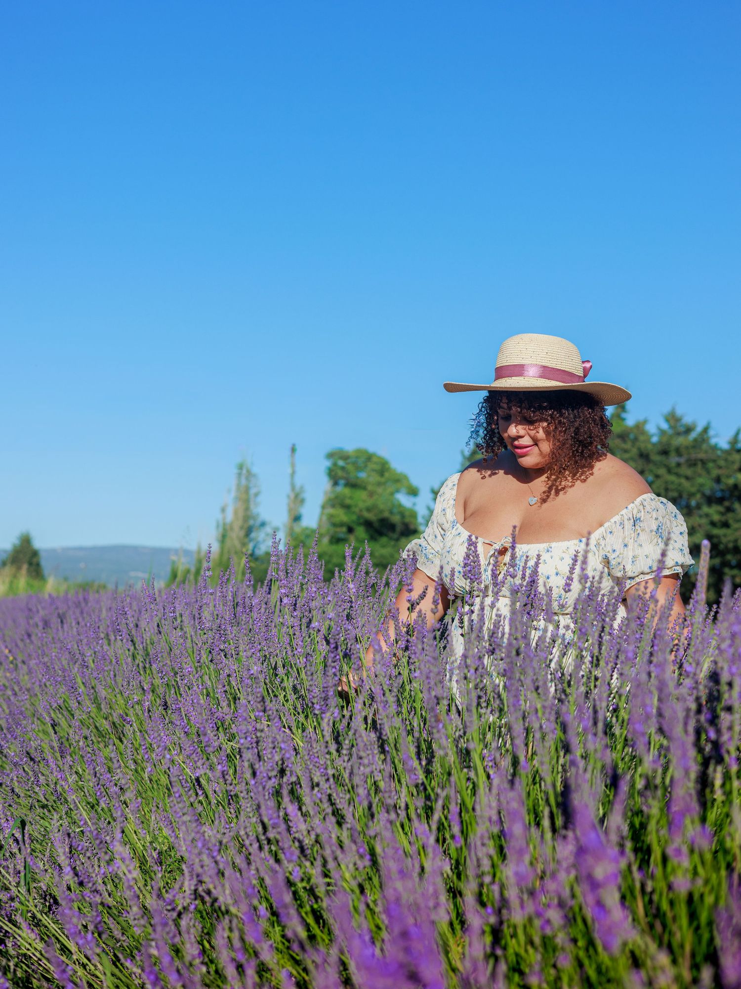 Une femme sourit dans un champ de lavande pendant une séance photo portrait pres d'Avignon