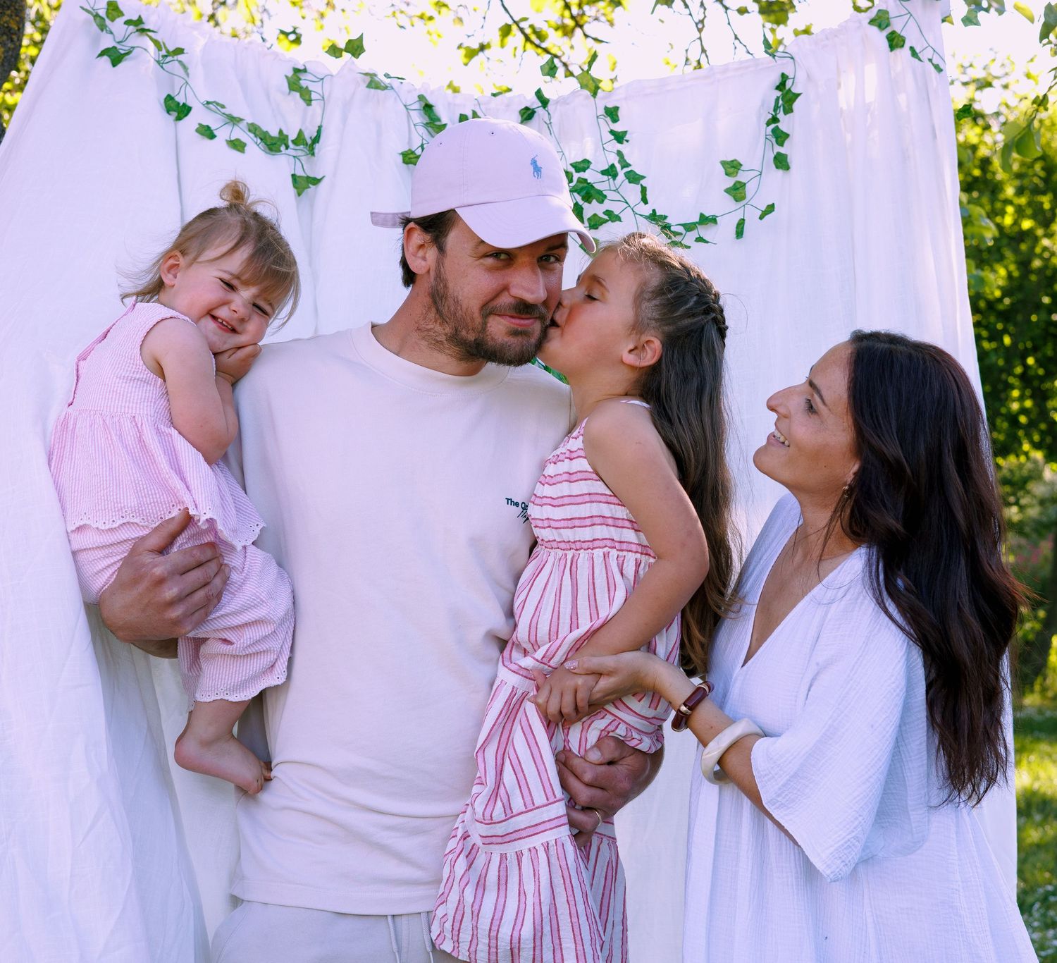 Une famille de quatre partage un moment tendre et complice pendant une séance photo famille en extérieur.