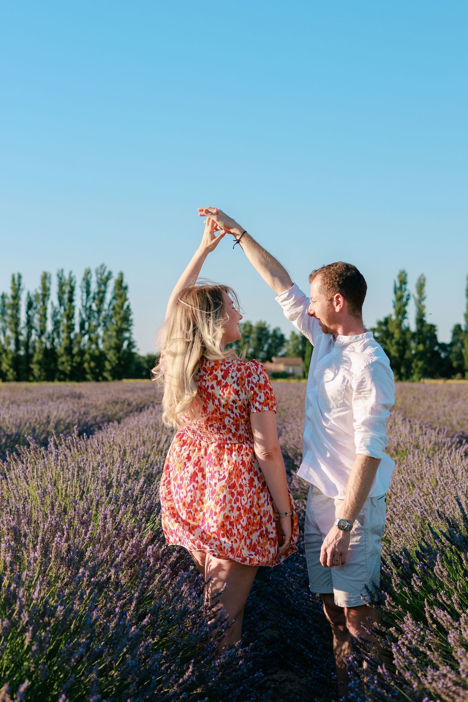 Un couple danse et s’amuse dans un champ de lavande pendant une séance photo grossesse en Vaucluse