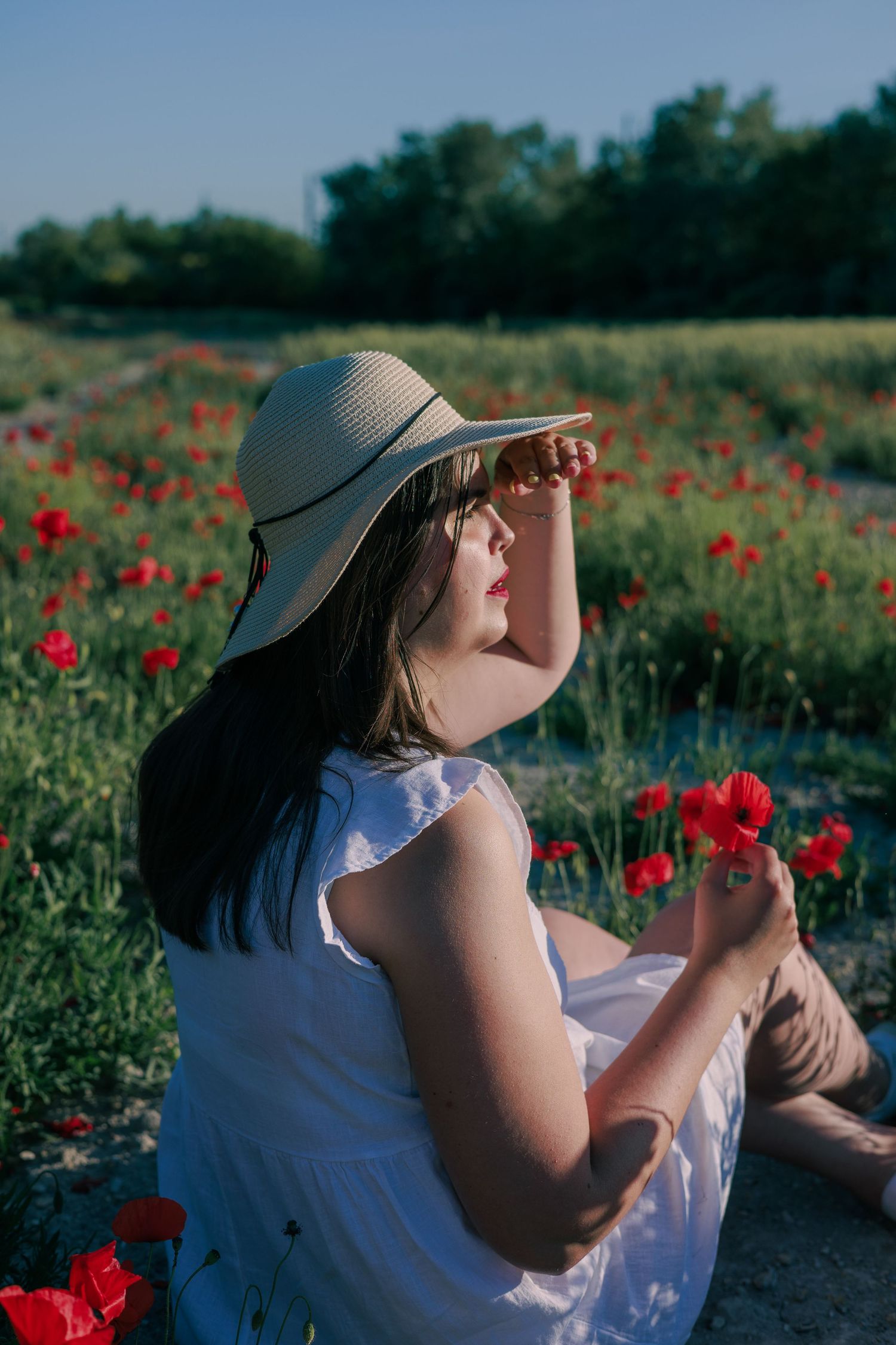 Une femme pose dans un champ de coquelicots pendant une séance photo portrait en extérieur.