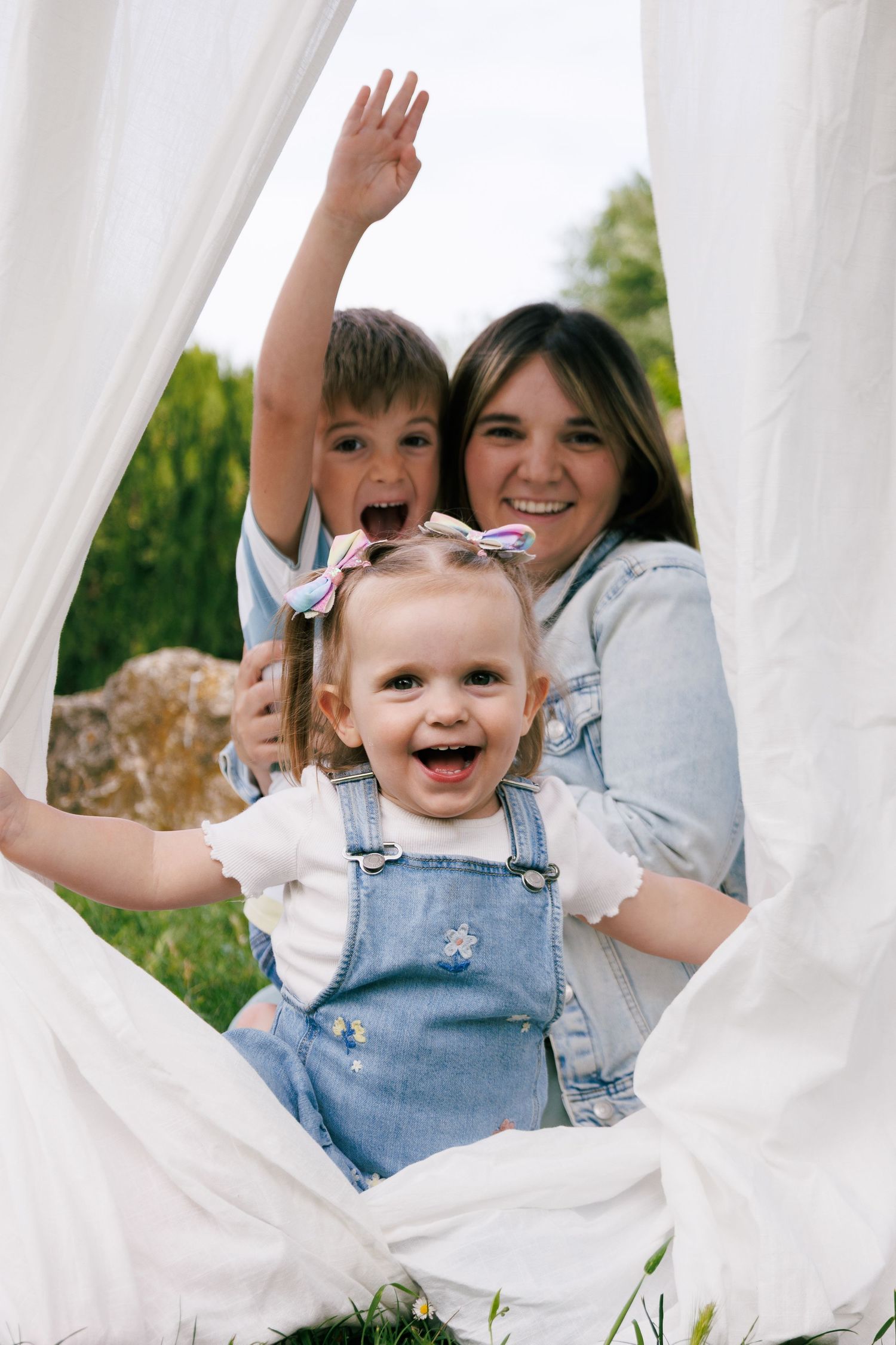 Une maman et ses enfants jouent et rigolent devant l’appareil photo pendant une séance photo famille.