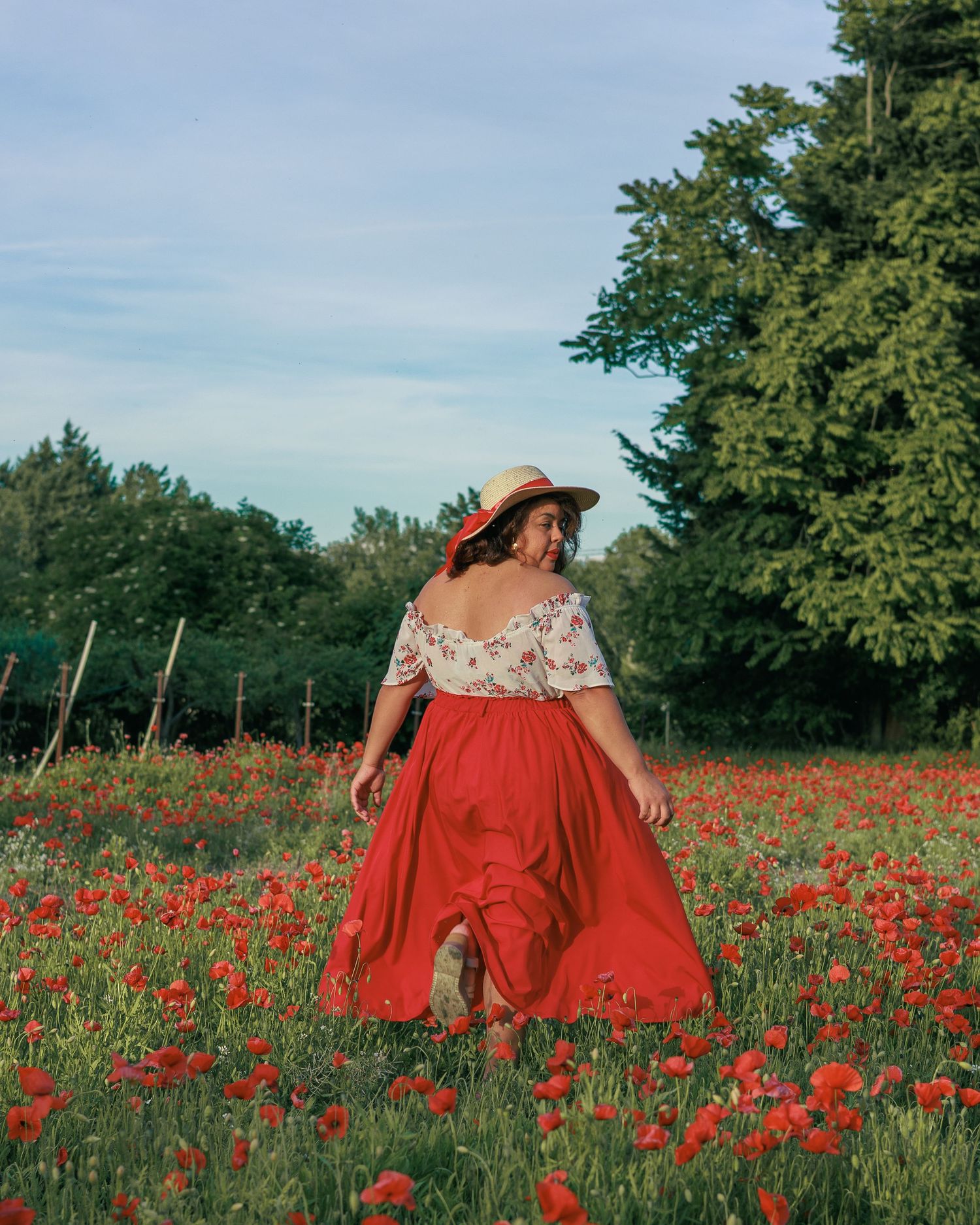 Une femme marche dans un champ de coquelicots pendant une séance photo portrait en extérieur.