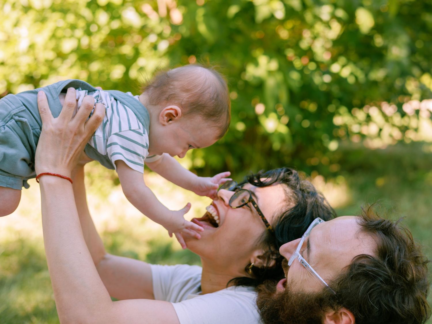 Des parents jouent avec leur bébé pendant une séance photo famille dans le parc