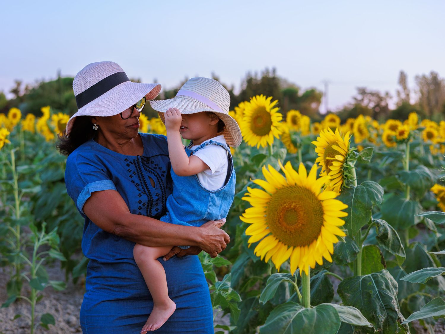 Une maman porte son enfant dans un champ de tournesols pendant une séance photo famille proche de Nimes