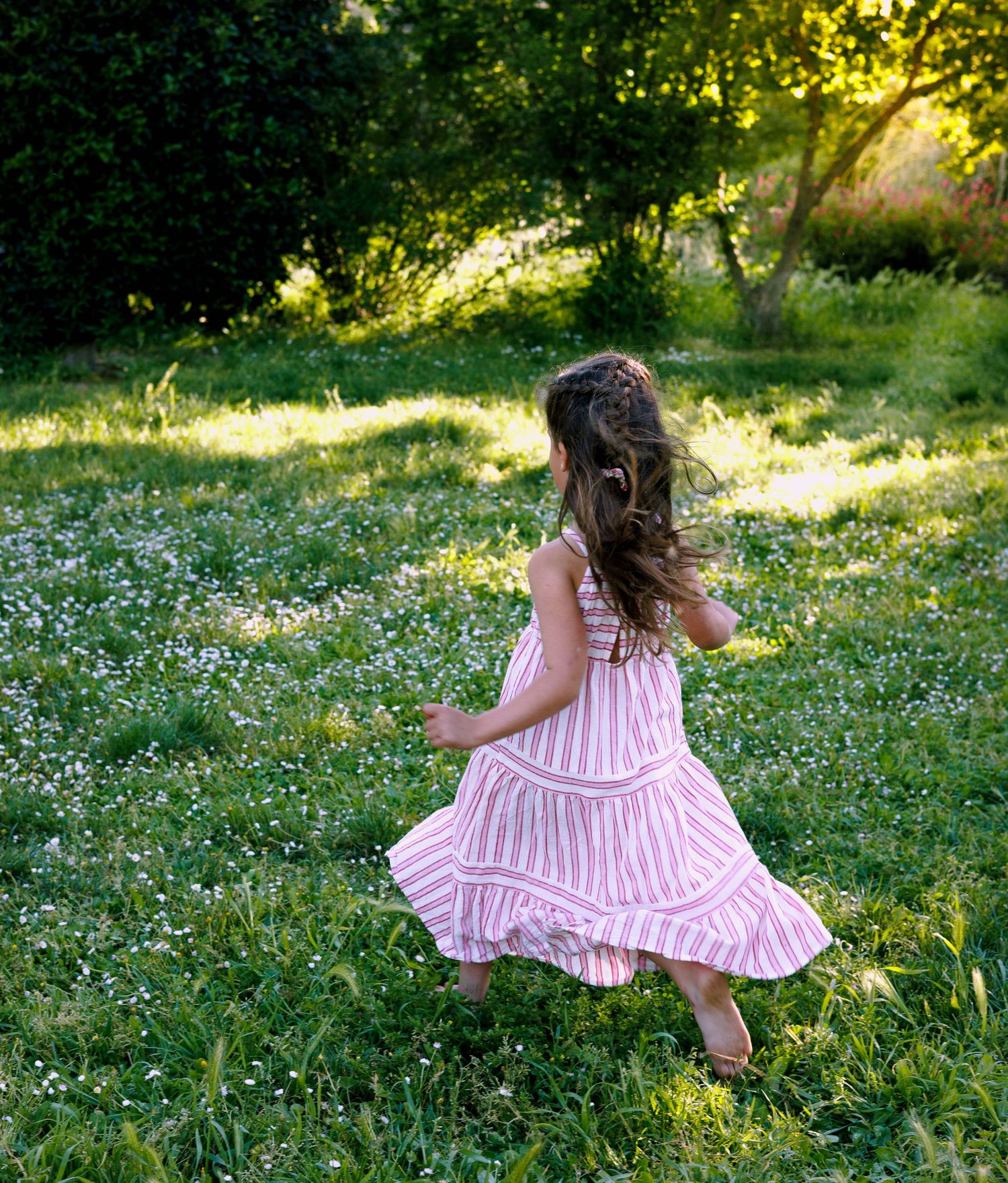 Une petite fille court dans l’herbe pendant une séance photo enfant en extérieur dans le Gard
