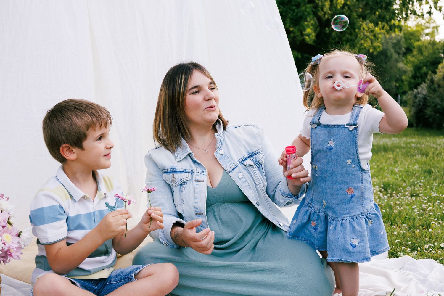 Une famille joue ensemble avec des bulles pendant une séance photo famille en extérieur.