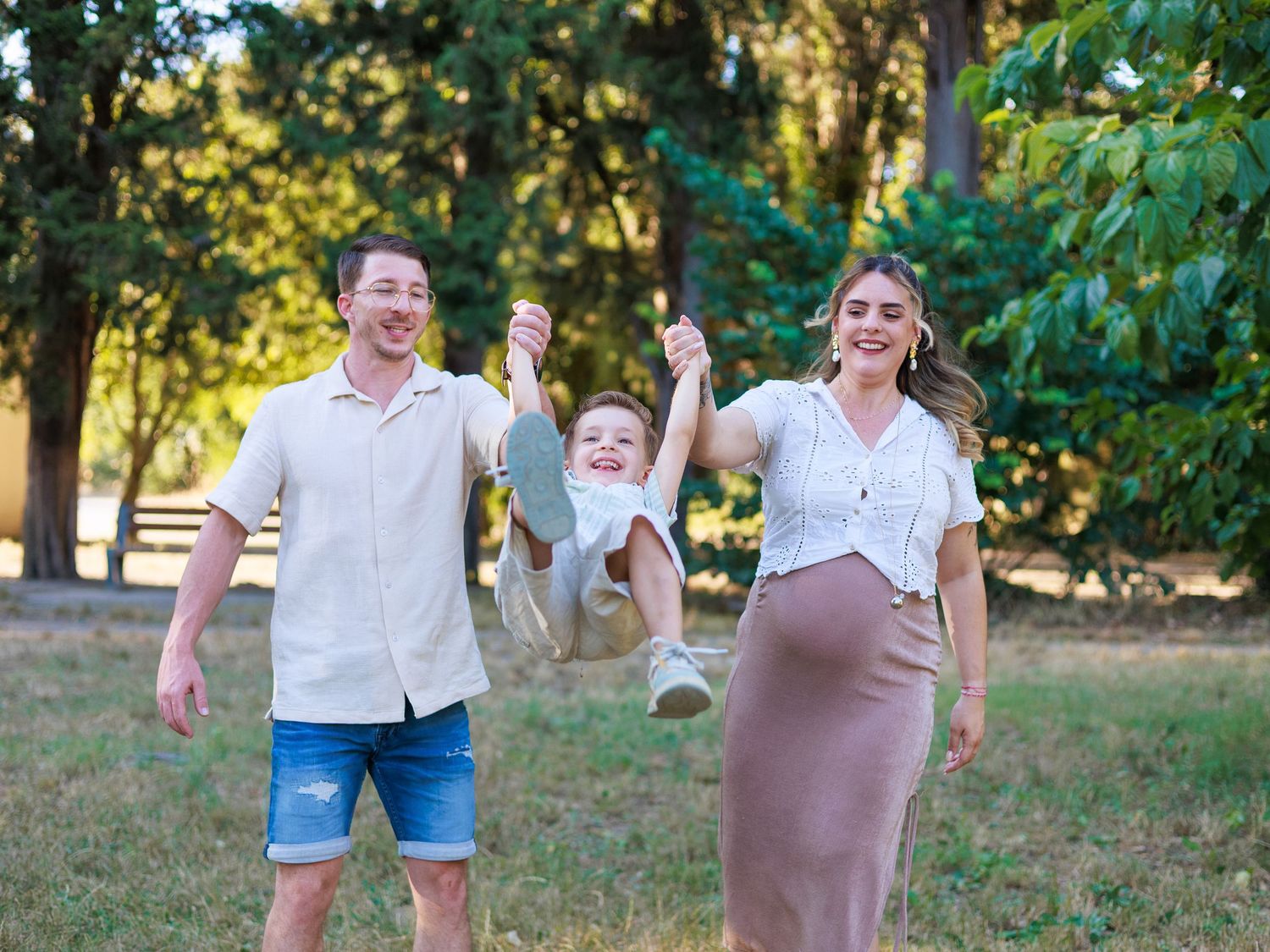 Une famille marche en s’amusant pendant une séance photo en extérieur, avec leur enfant entre les deux parents.