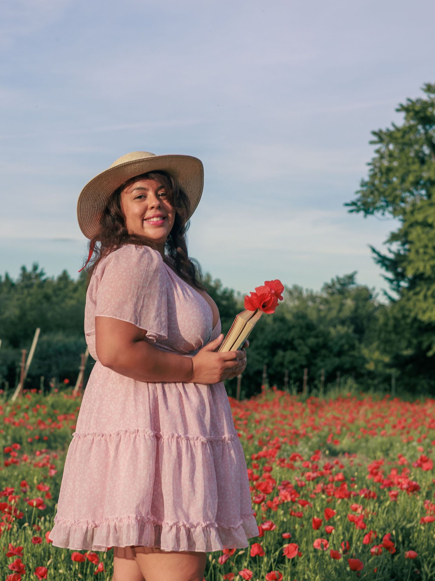 Une femme sourit dans un champ de coquelicots pendant une séance photo portrait.