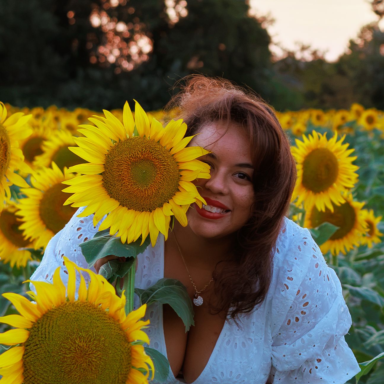 Une femme sourit au milieu d’un champ de tournesols pendant une séance photo portrait pres de Pujaut