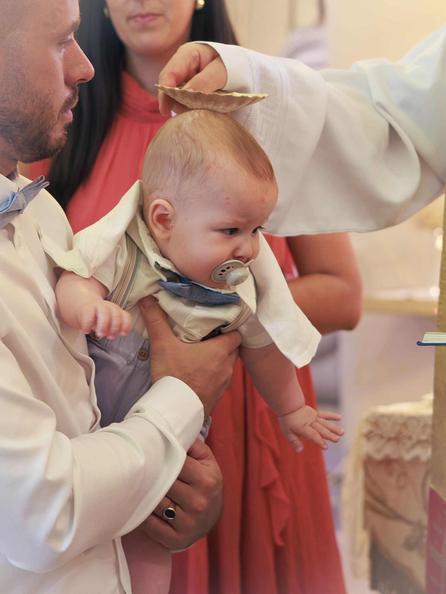 Un bébé et ses parents pendant la cérémonie de baptême.